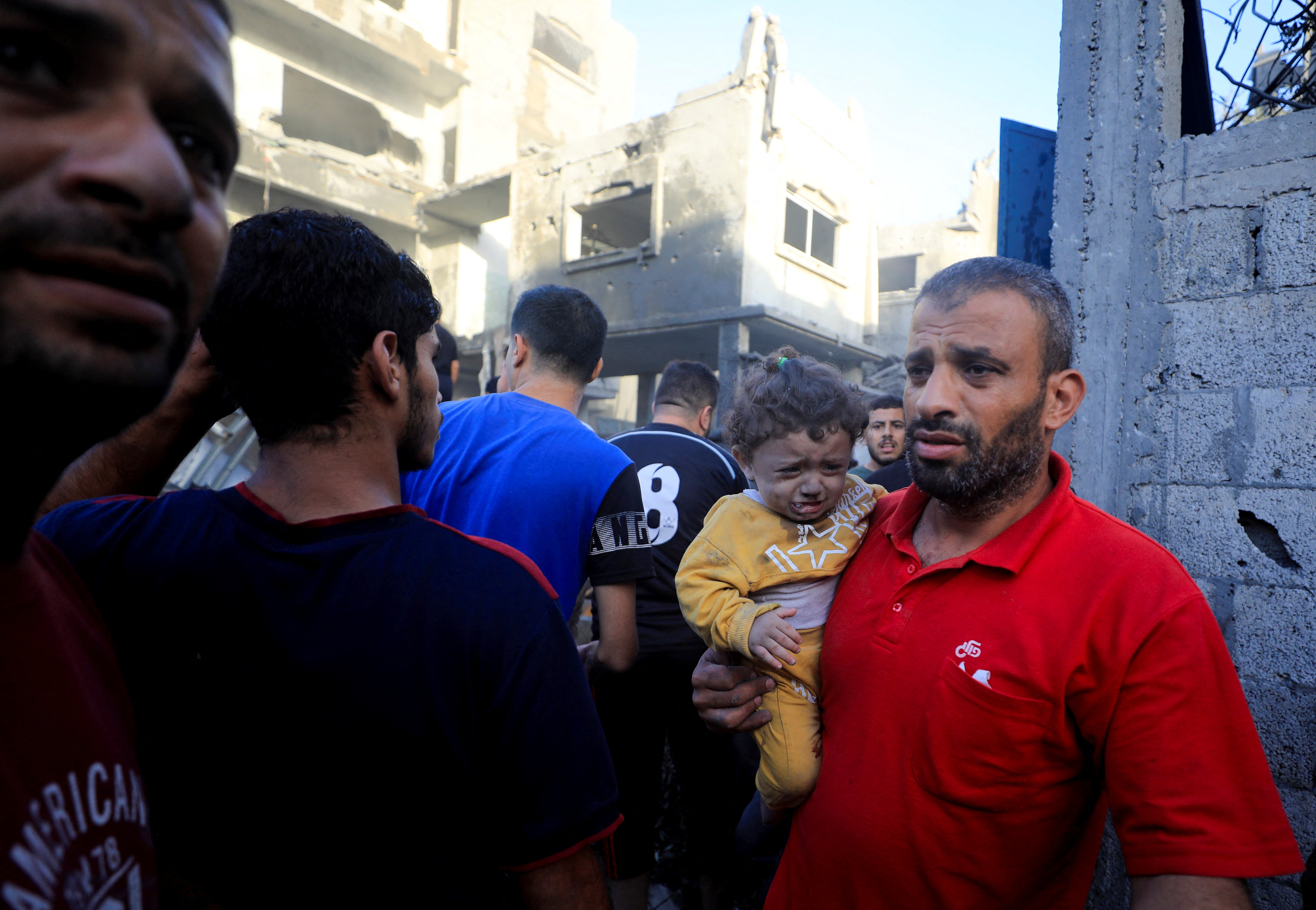 Palestinians gather at the site of Israeli strikes on houses, amid the ongoing conflict between Israel and Palestinian Islamist group Hamas, in Maghazi refugee camp in the central Gaza Strip