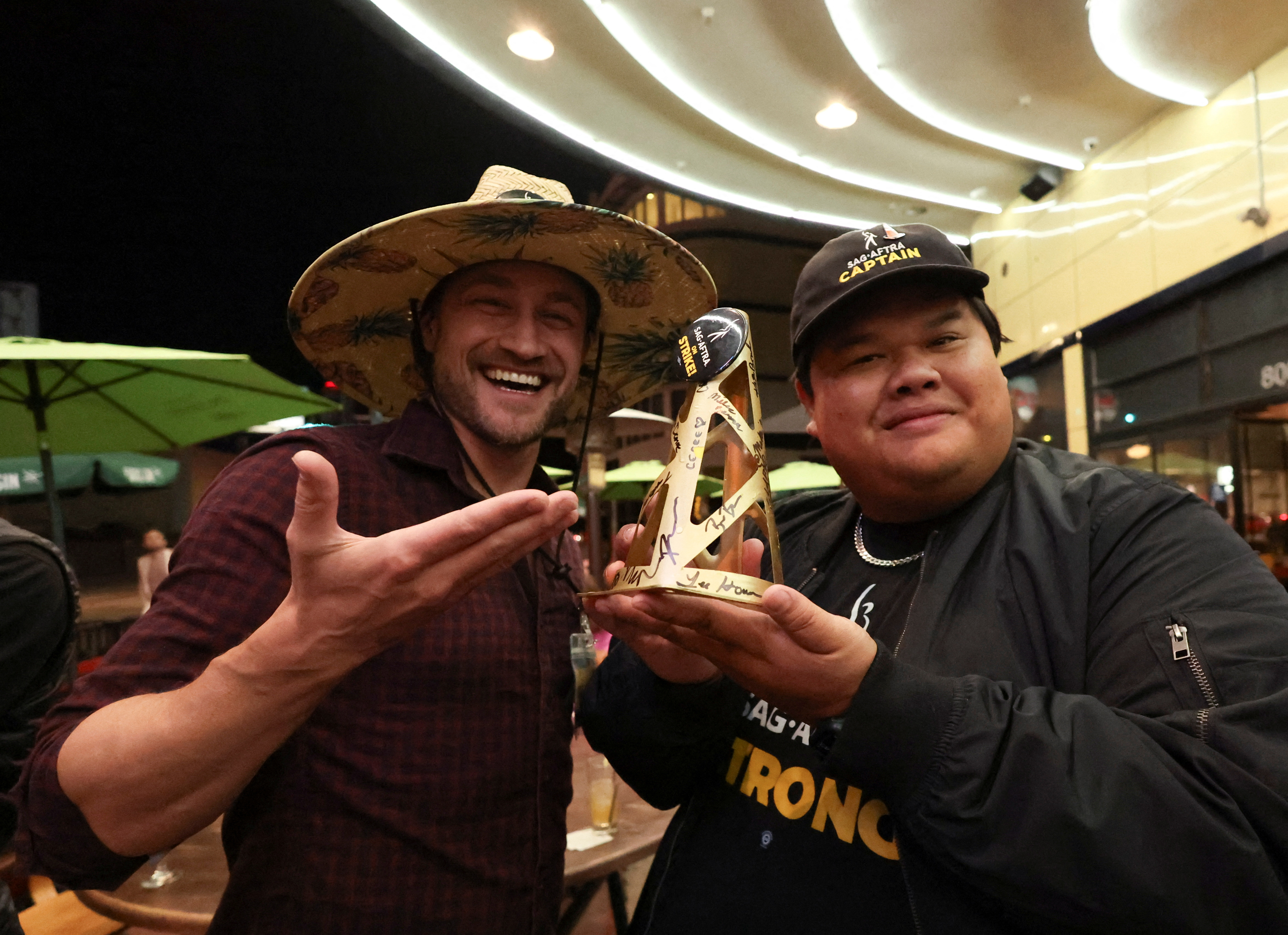 Union negotiators celebrate their preliminary deal with studios. They're in a conference room and are holding a golden cone.