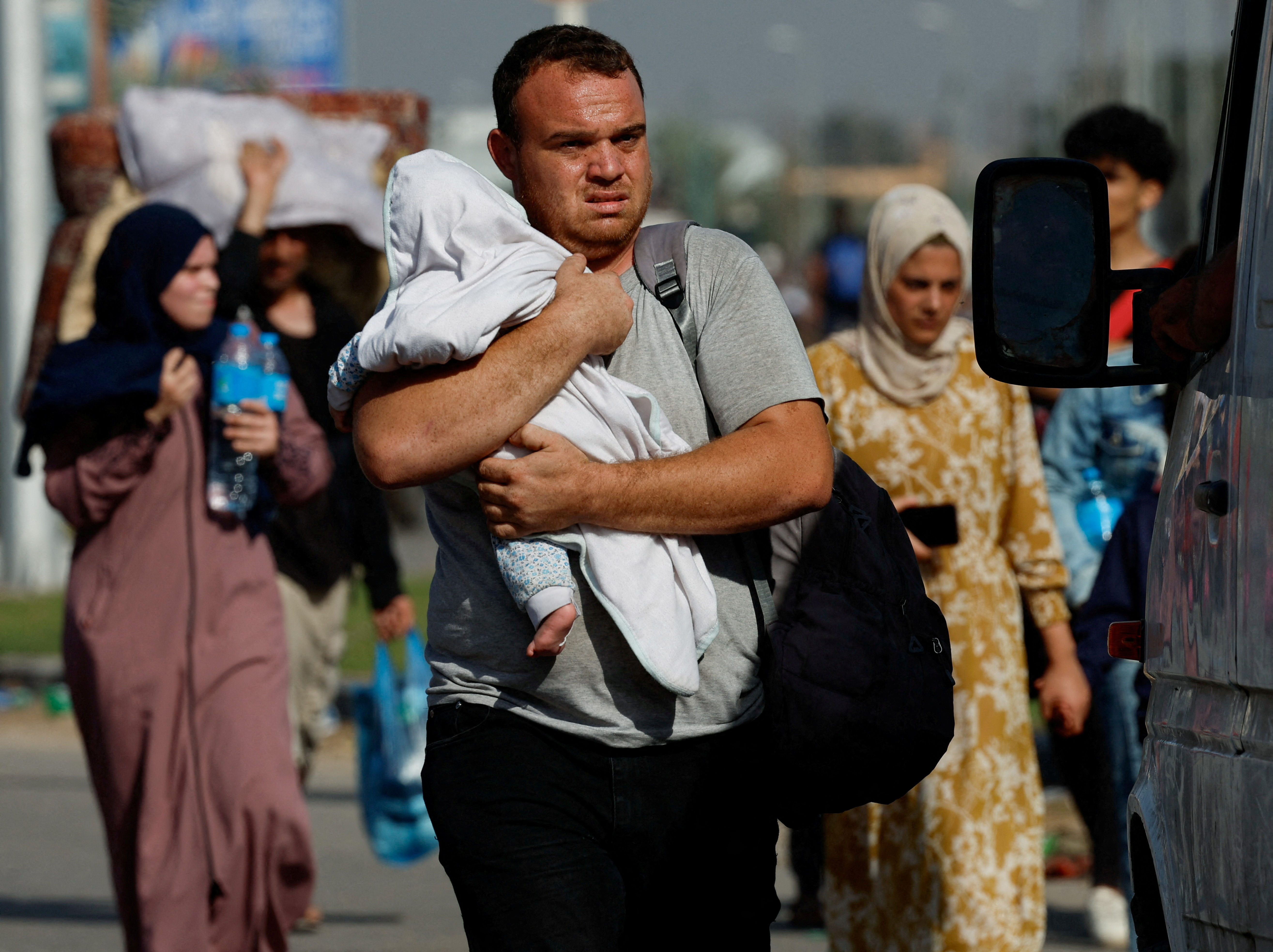 A man carries a child as Palestinians fleeing north Gaza walk towards the south, amid the ongoing conflict between Israel and Palestinian Islamist group Hamas, in the central Gaza Strip, November 9, 2023.