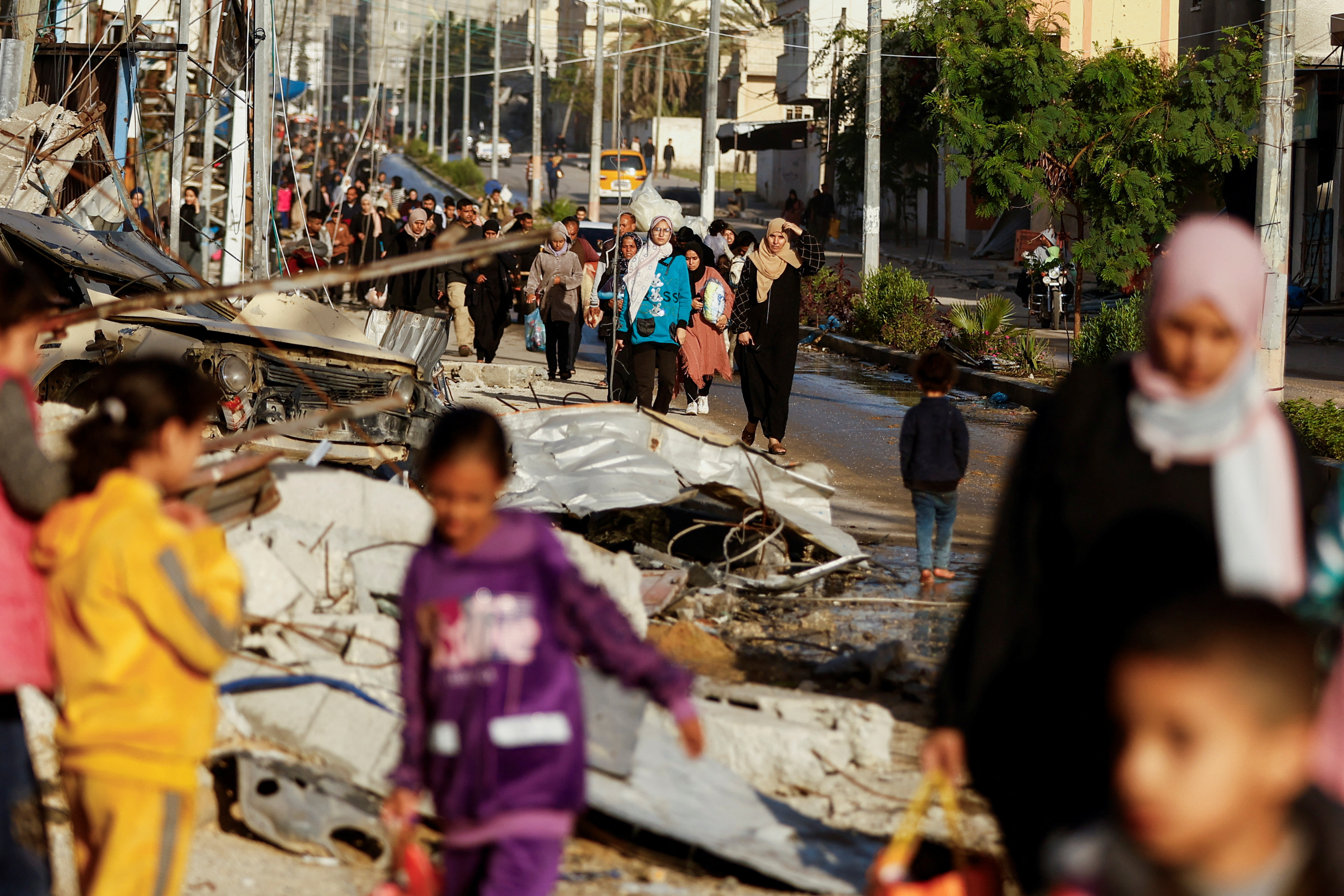 Displaced Palestinians walk on a road as they return to their home, during a temporary truce between Hamas and Israel, in Khan Younis in the southern Gaza Strip