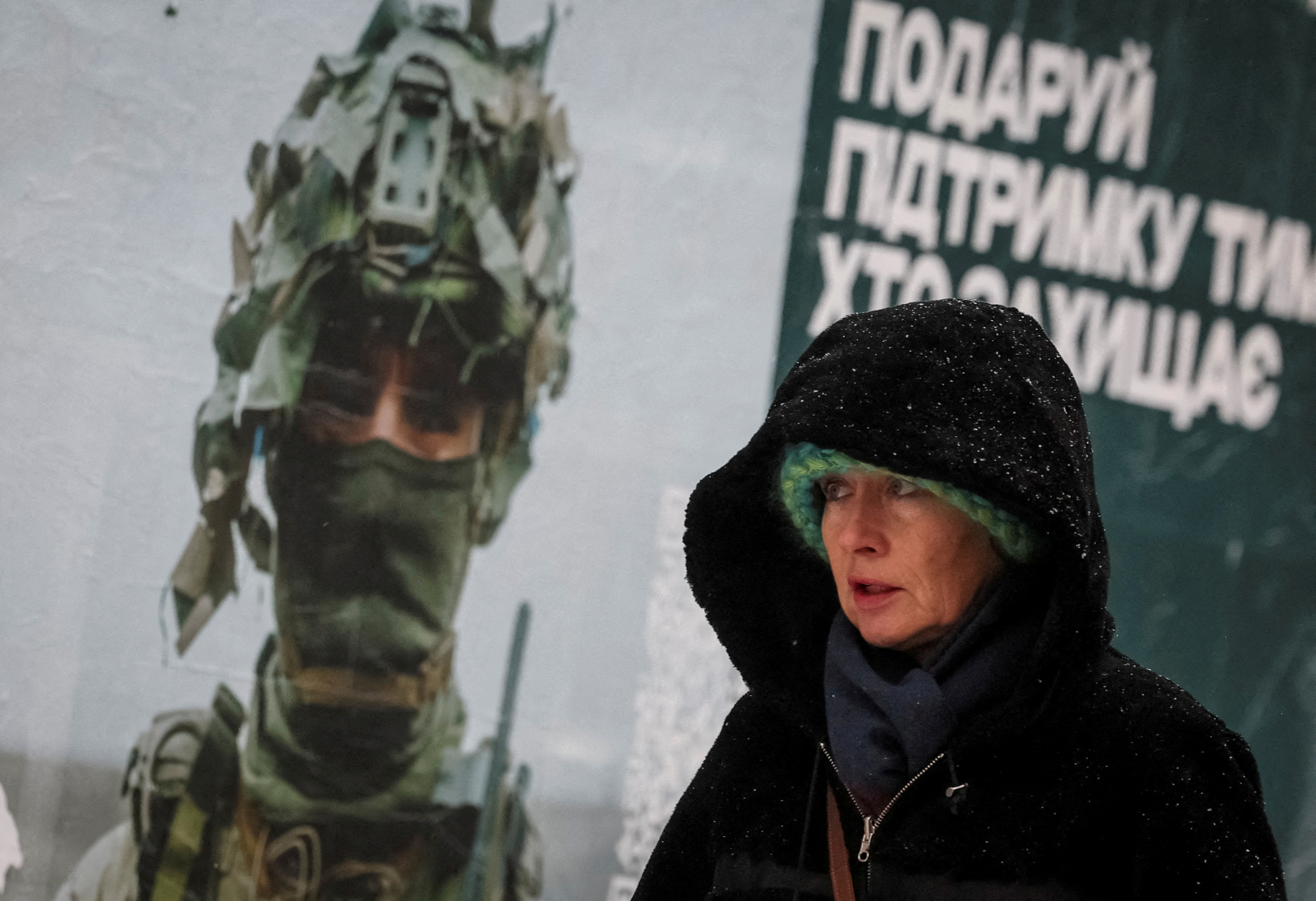 FILE PHOTO: A woman walks past an advertising poster depicting a Ukrainian serviceman during a snowfall in Kyiv, Ukraine November 27, 2023. REUTERS/Gleb Garanich/File Photo