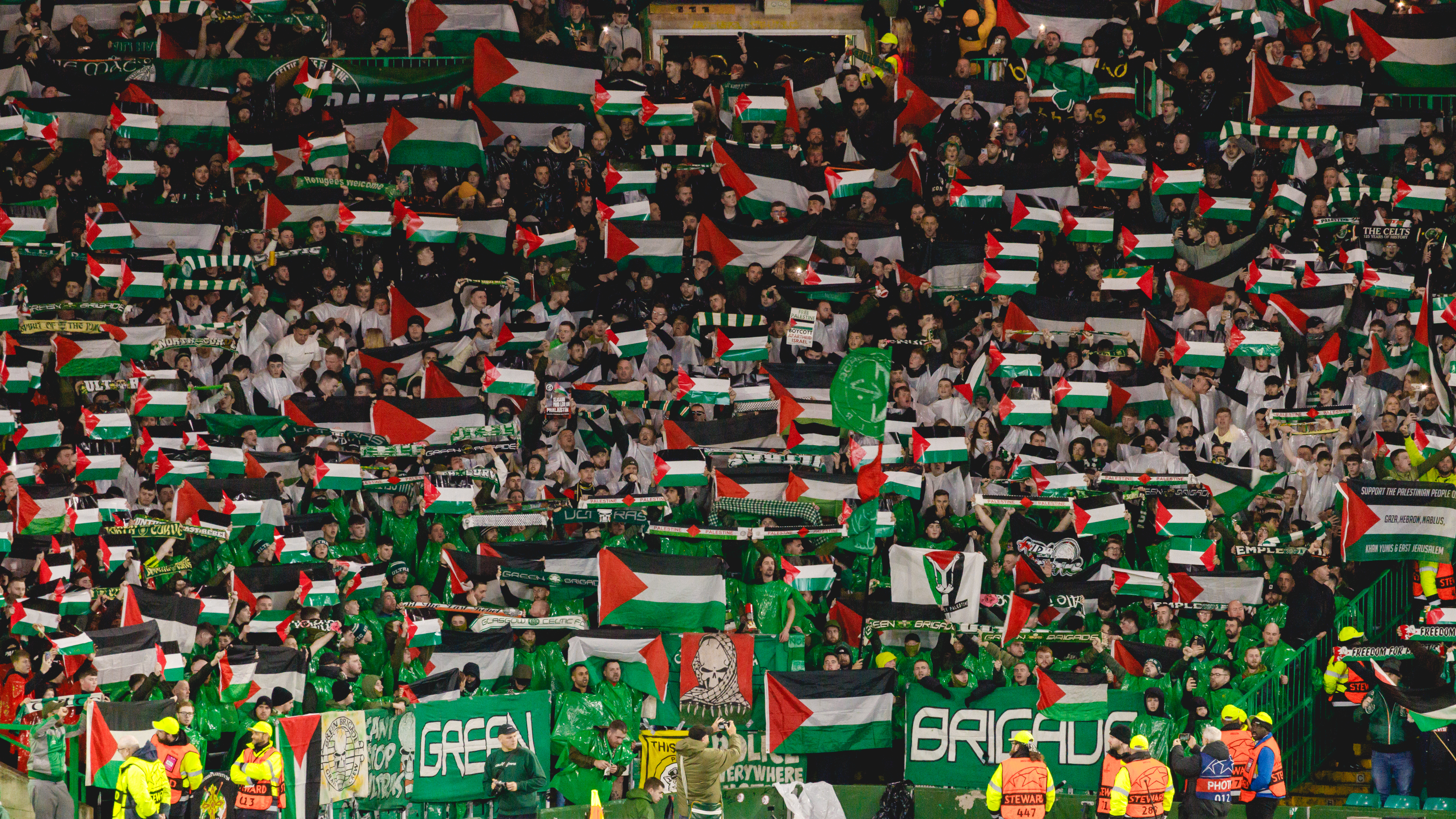 Fans of Celtic Football Club wave Palestine flags during their UEFA Champions League match against Atletico Madrid at Celtic Park, Glasgow, UK on October 25 2023 [Hargi/Al Jazeera]