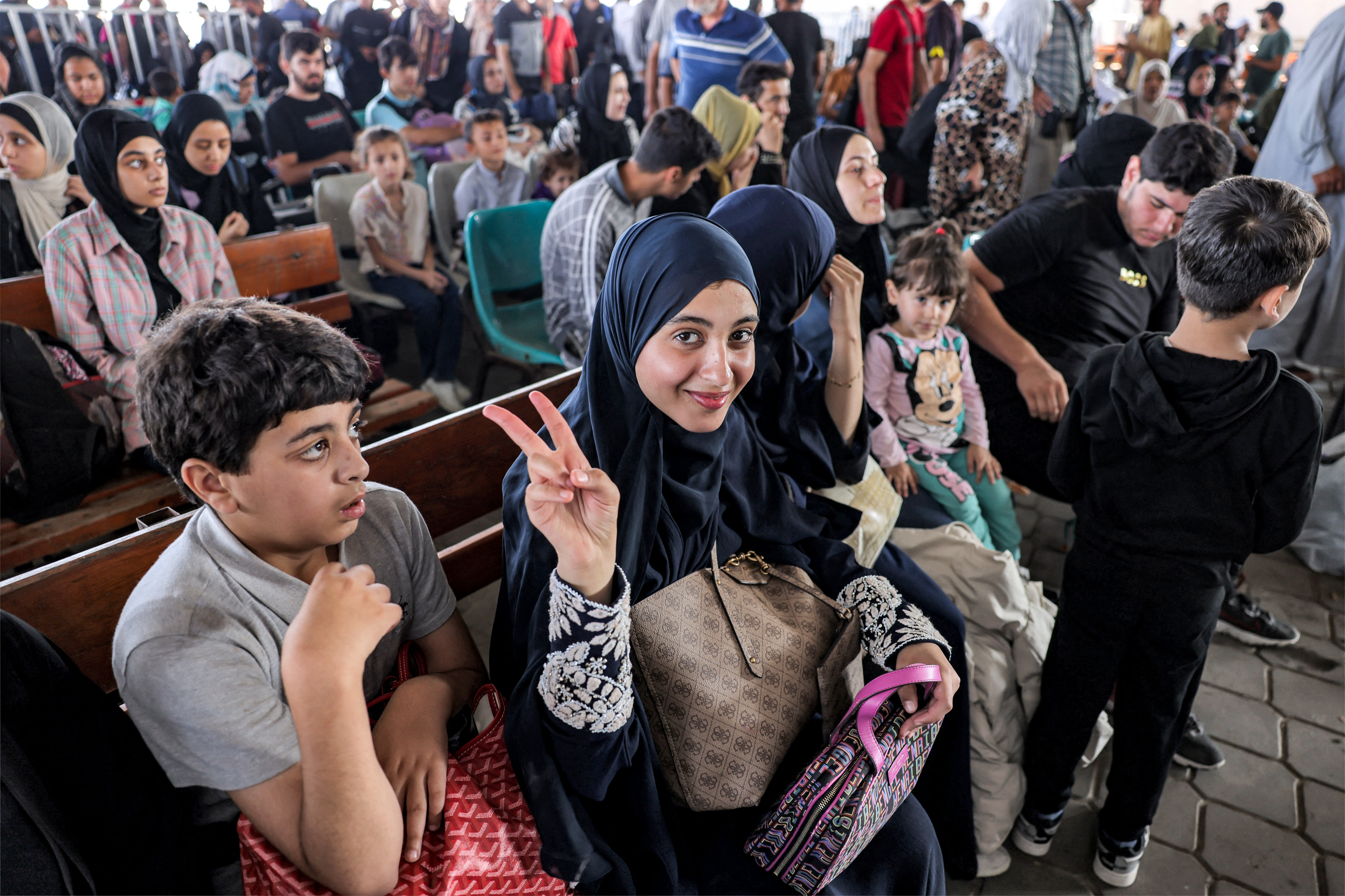 People sit in the waiting area at the Rafah border crossing in the southern Gaza Strip before crossing into Egypt on November 1, 2023