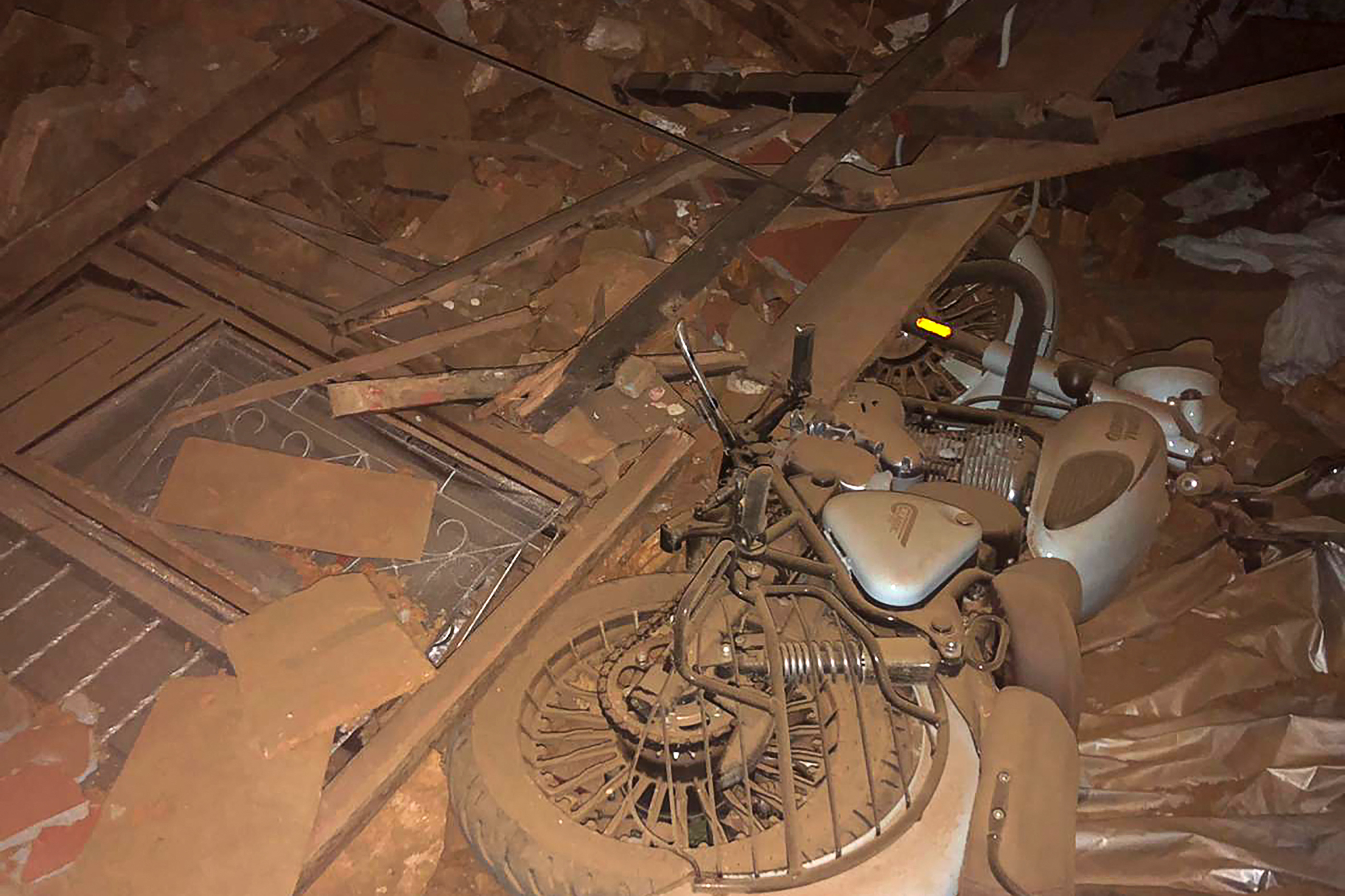 A motorbike tipped on its side and broken windows after the earthquake. They are covered in reddish-brown mud.