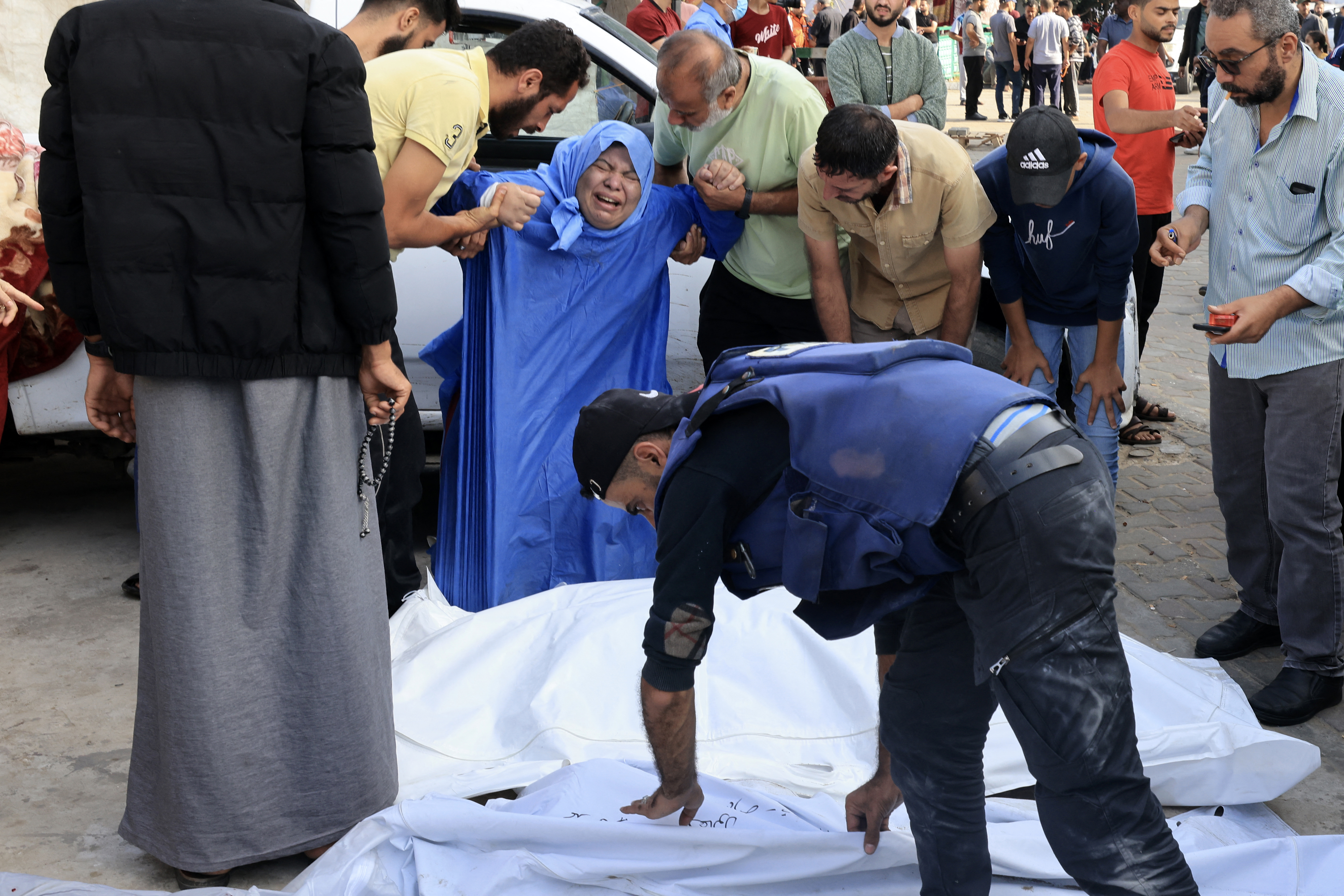 A family member reacts as Palestinian cameraman Mohammed Alaloul (bottom) covers the body of a relative killed in an Israeli strike on the Al-Maghazi refugee camp in Deir Balah in the central Gaza Strip.