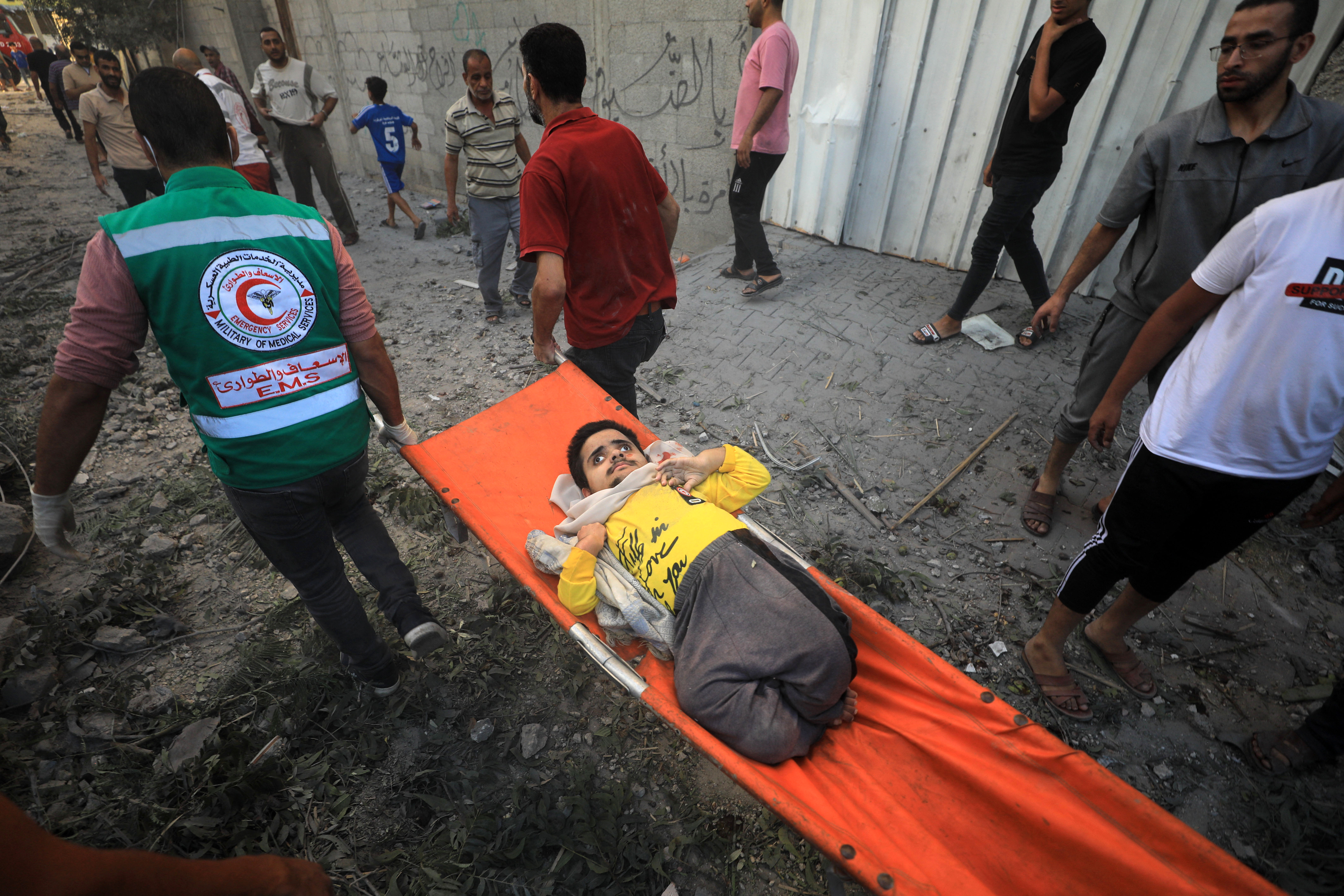 Rescuers carry a youth with disabilities as people flee following Israeli air strikes on a neighbourhood in the al-Maghazi refugee camp in the central Gaza Strip on November 6