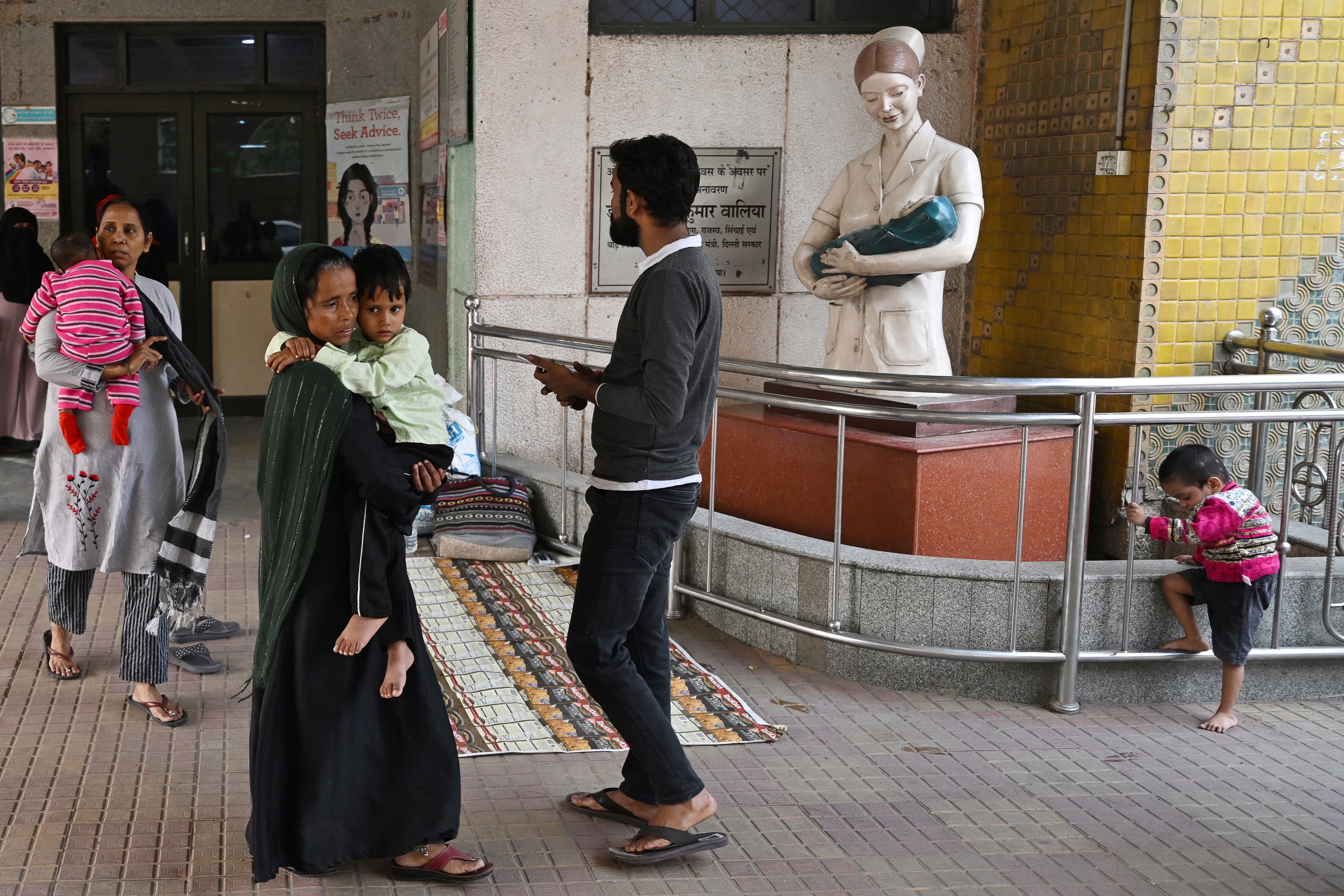 In this picture taken on November 7, 2023, women carrying children leave after receiving treatment at the government-run Chacha Nehru Bal Chikitsalaya children hospital in New Delhi.