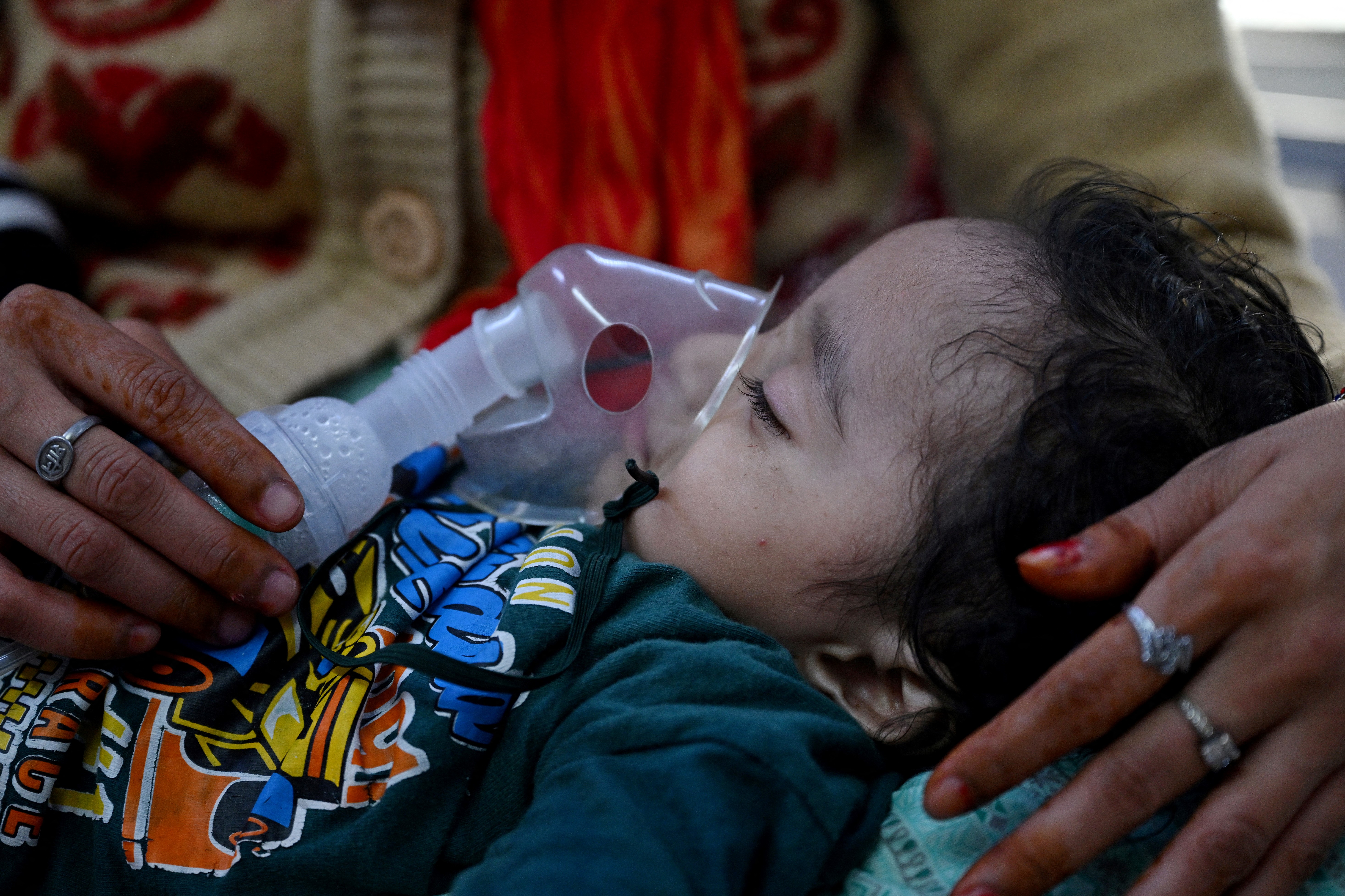 In this picture taken on November 7, 2023, a mother assists her child to breathe with the help of a nebuliser at the emergency ward of the government-run Chacha Nehru Bal Chikitsalaya children hospital in New Delhi.