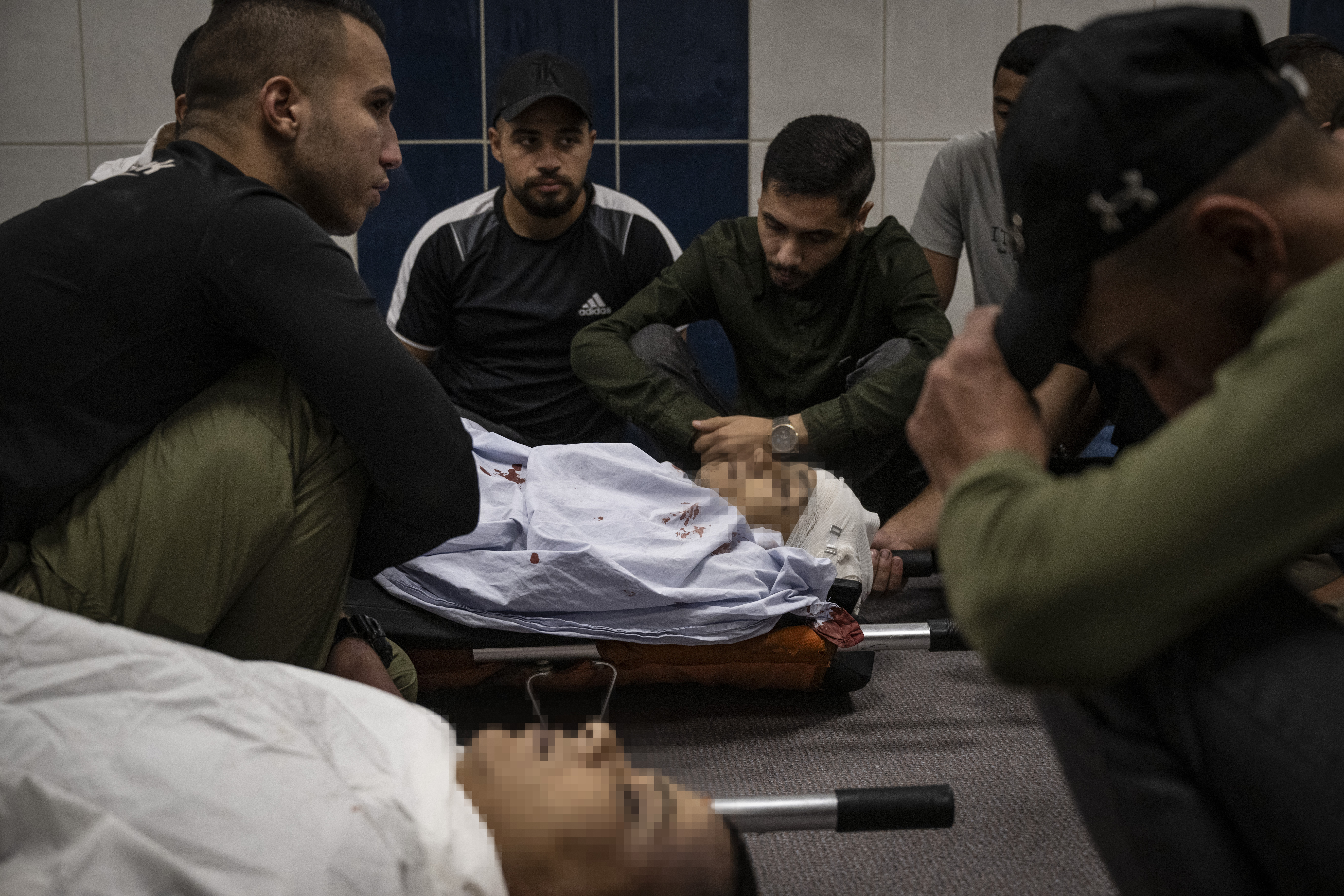People surround the bodies of two Palestinians killed during confrontations with Israeli forces in the occupied West Bank city of Jenin, at the morgue of a hospital