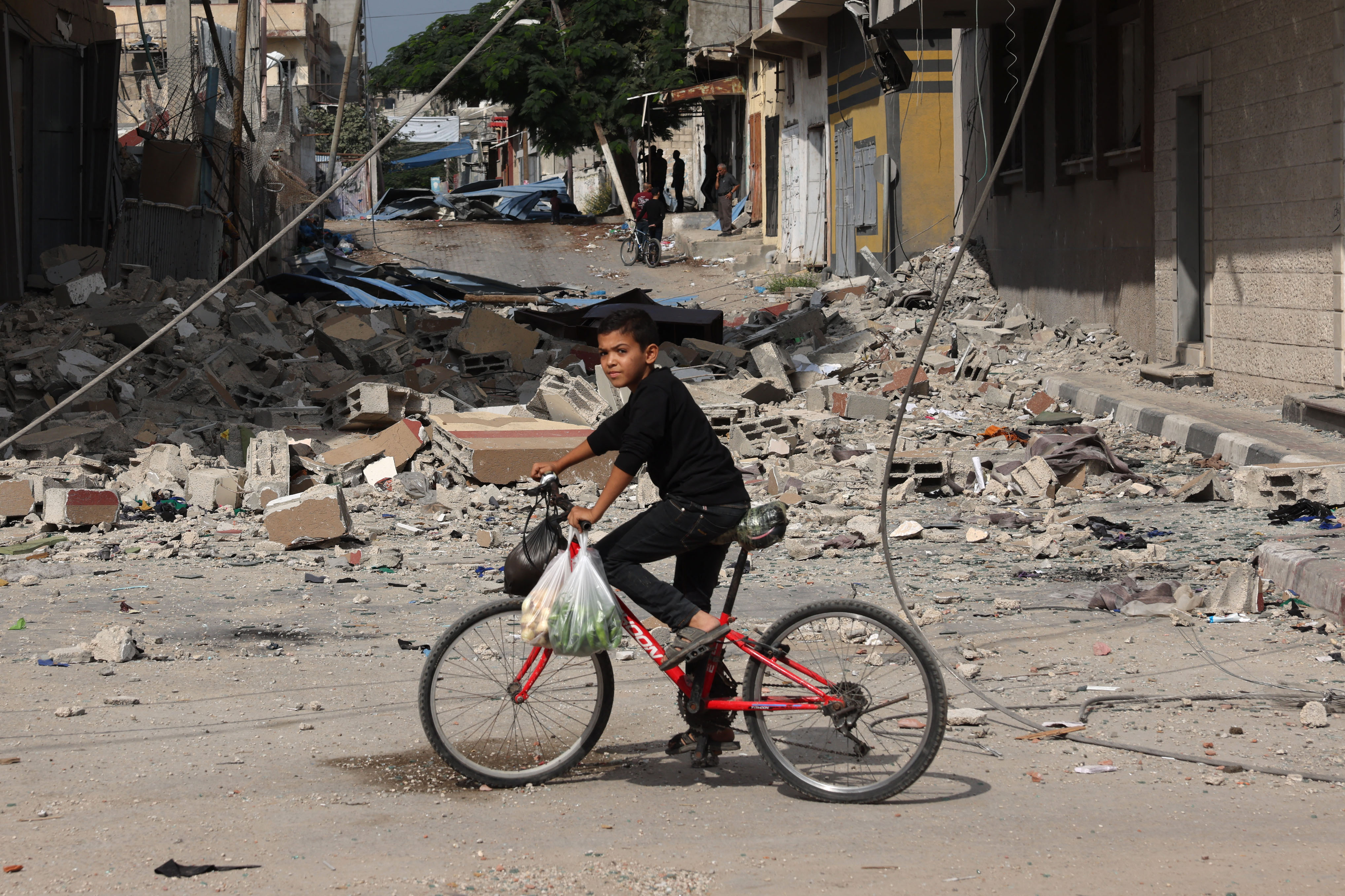 A Palestinian boy rides a bicycle amidst debris in Rafah