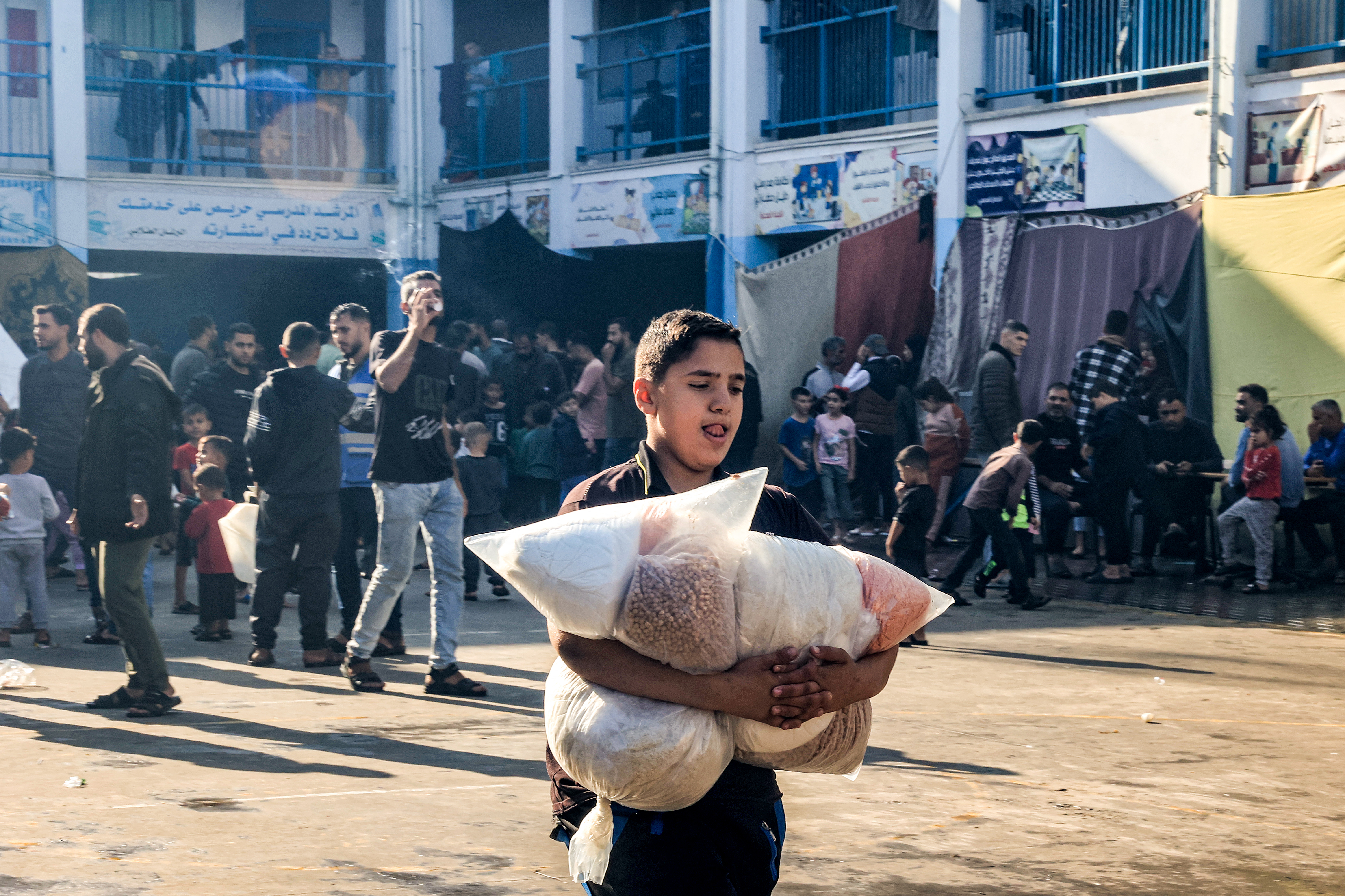 A boy walks with sacks of food supplies through a yard at a school run by the United Nations Relief and Works Agency for Palestine Refugees in the Near East (UNRWA) in Rafah in the southern Gaza Strip.