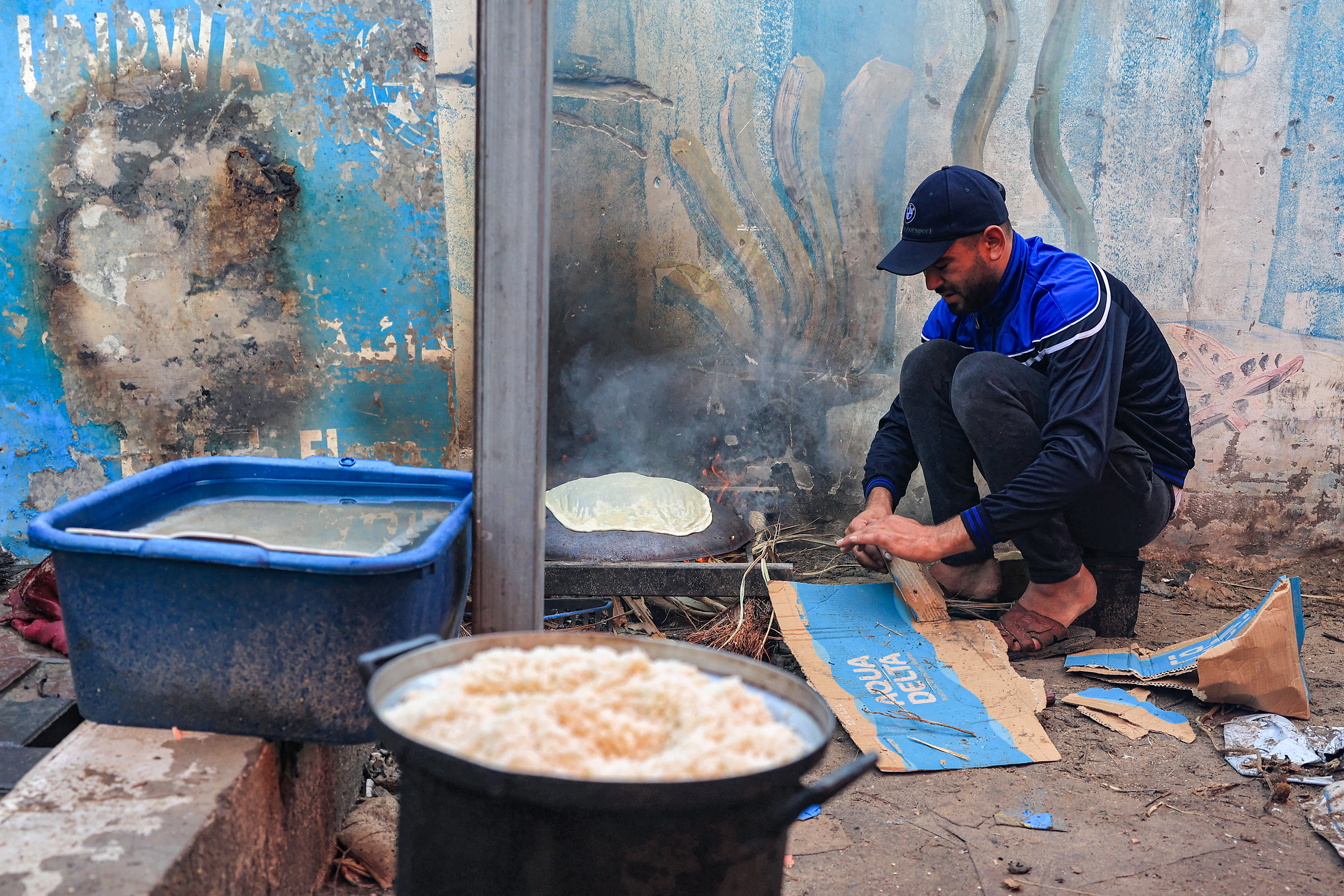 A man prepares traditional unleavened bread on an open fire at a school run by the United Nations Relief and Works Agency for Palestine Refugees in the Near East (UNRWA) in Rafah in the southern Gaza Strip.