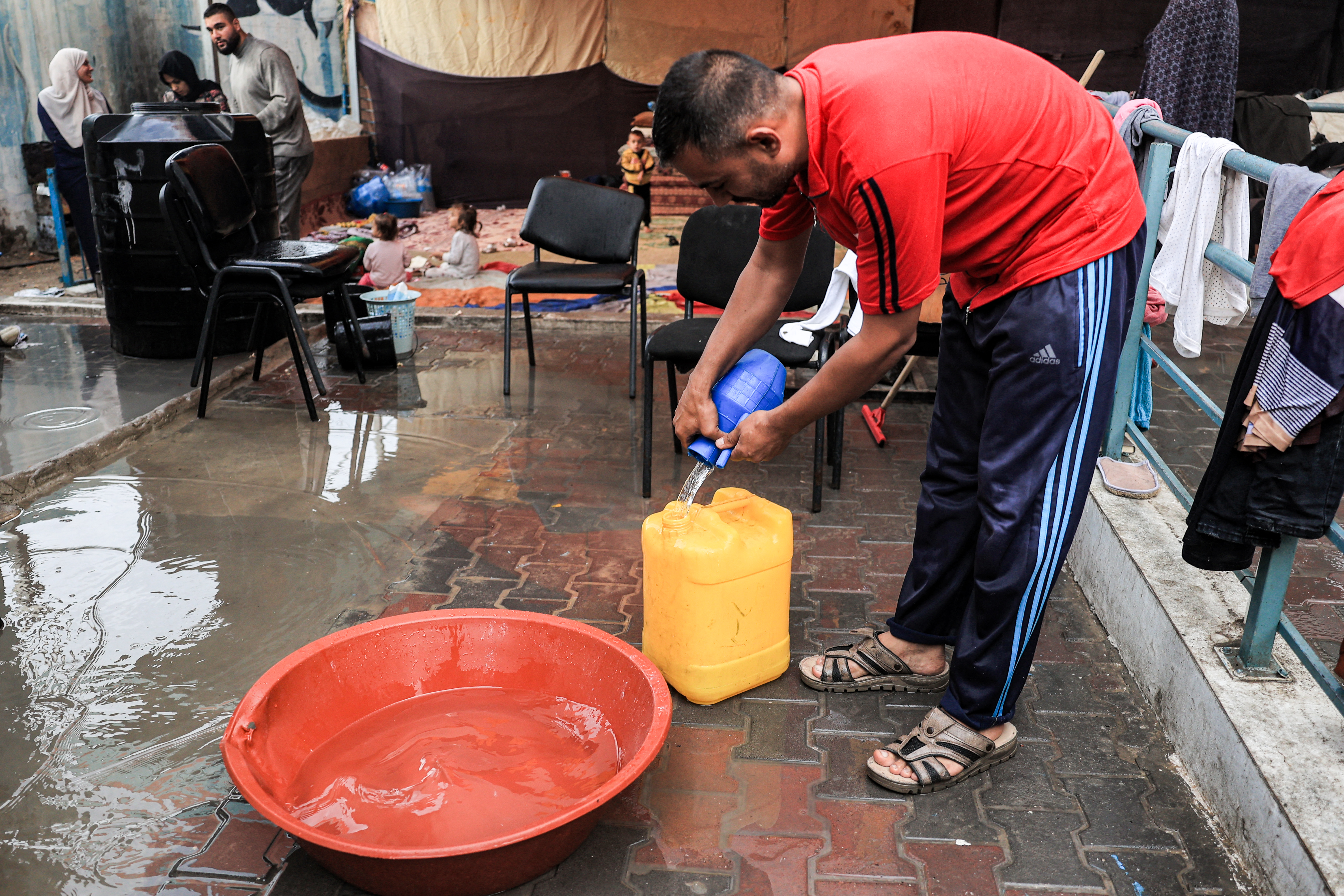 A man fills a jerrycan with water collected from raindrops falling into a basin, at a school run by the United Nations Relief and Works Agency for Palestine Refugees in the Near East (UNRWA) in Rafah in the southern Gaza Strip.
