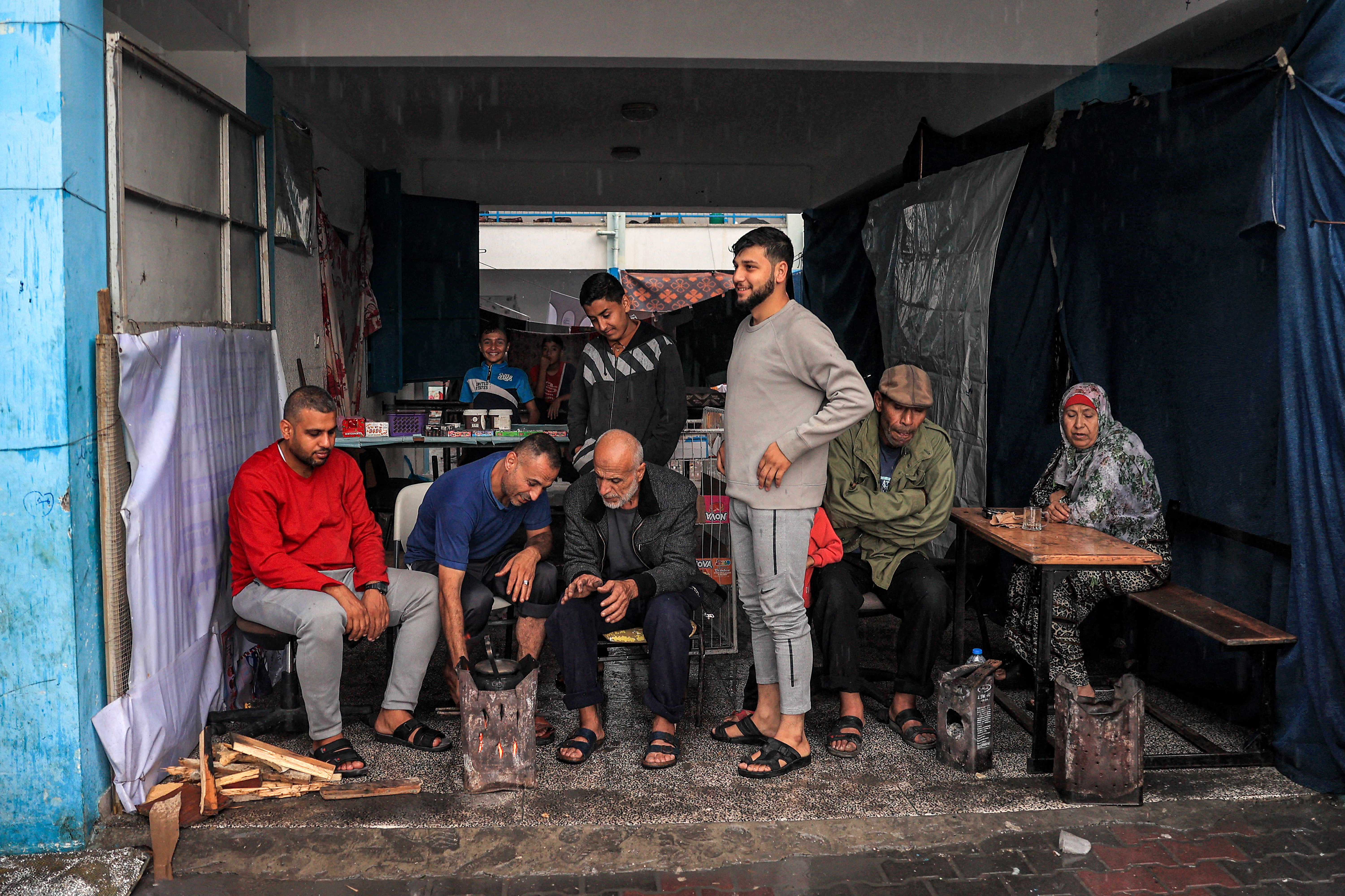 People take shelter from the rain in a hall overlooking the yard at a school run by the United Nations Relief and Works Agency for Palestine Refugees in the Near East (UNRWA), in Rafah in the southern Gaza Strip.
