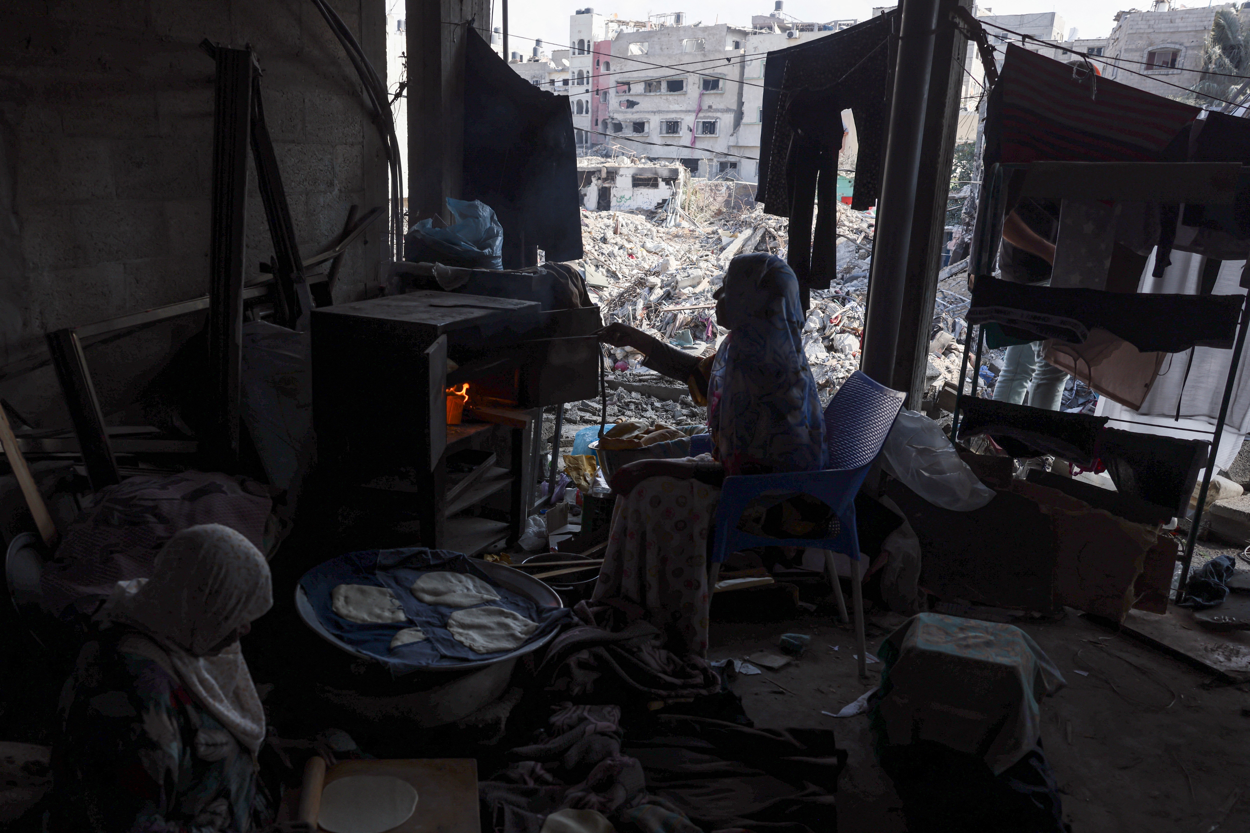 A Palestinian woman bakes bread in her home destroyed during the Israeli bombardment of Gaza, in Bureij in the central of Gaza Strip.