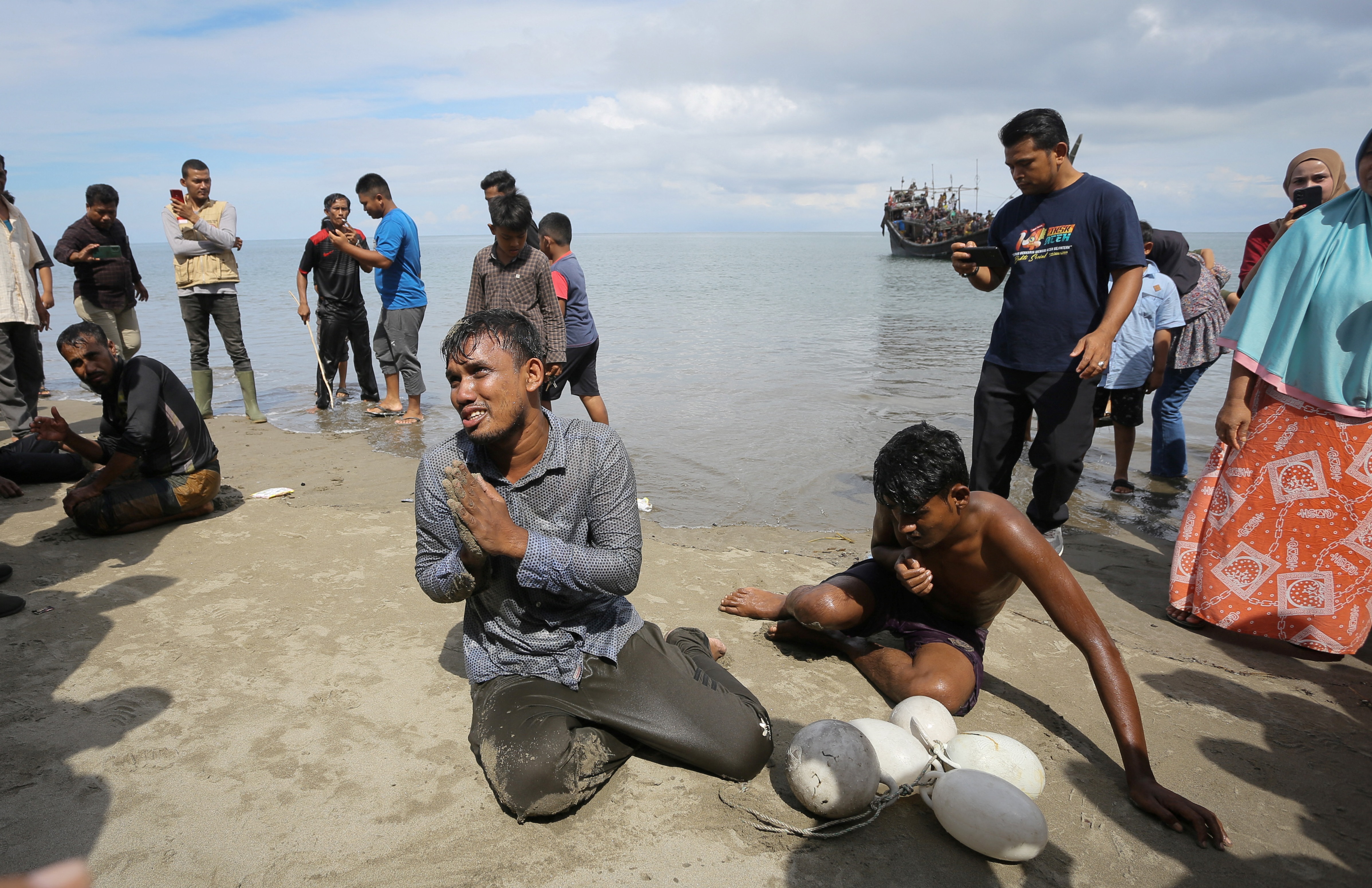 Newly arrived Rohingya refugees react after reaching the beach by swimming as others are stranded on a boat after the nearby community decided not to allow them to land but gave them water and food in Pineung, Aceh province.