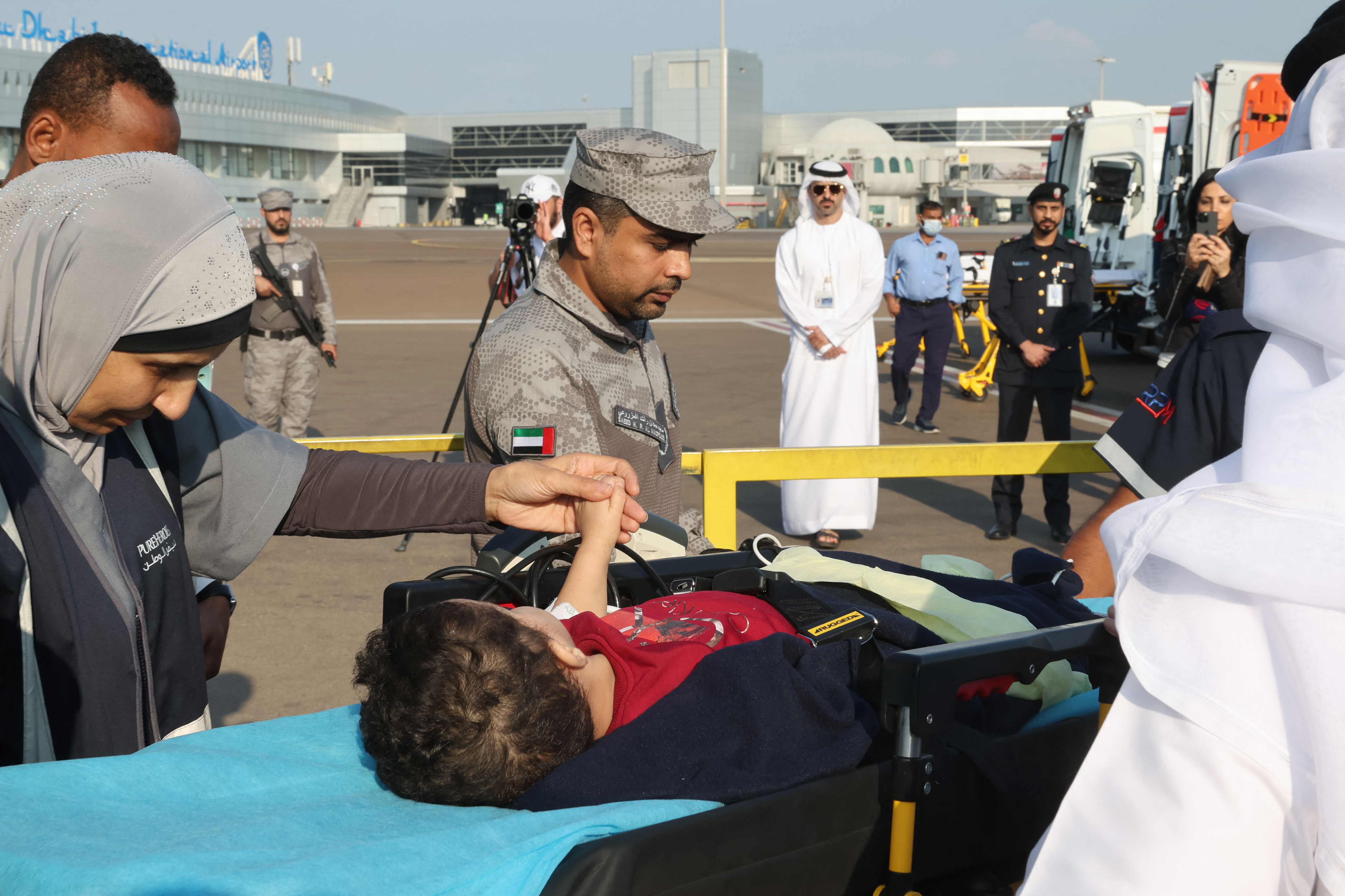 Volunteers transport a wounded Palestinian child off the plane upon their arrival in Abu Dhabi on November 18, 2023, after being evacuated from Gaza as part of a humanitarian mission organised by the United Arab Emirates