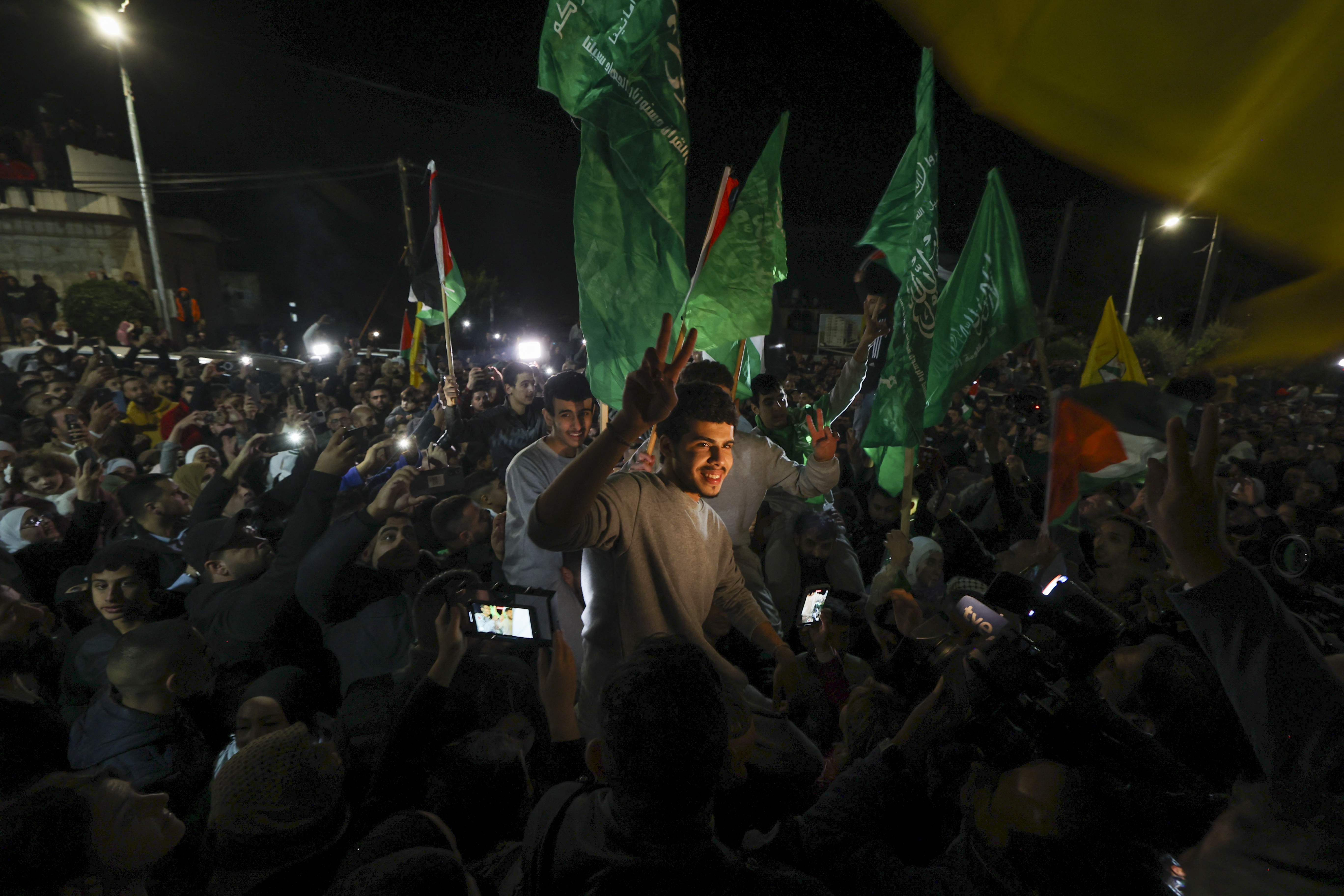 Palestinian prisoners (wearing grey jumpers) that were released from the Israeli Ofer military facility in exchange for hostages freed by Hamas in Gaza, wave flags and chant slogans as they are paraded in Baytunia in the occupied West Bank on November 24