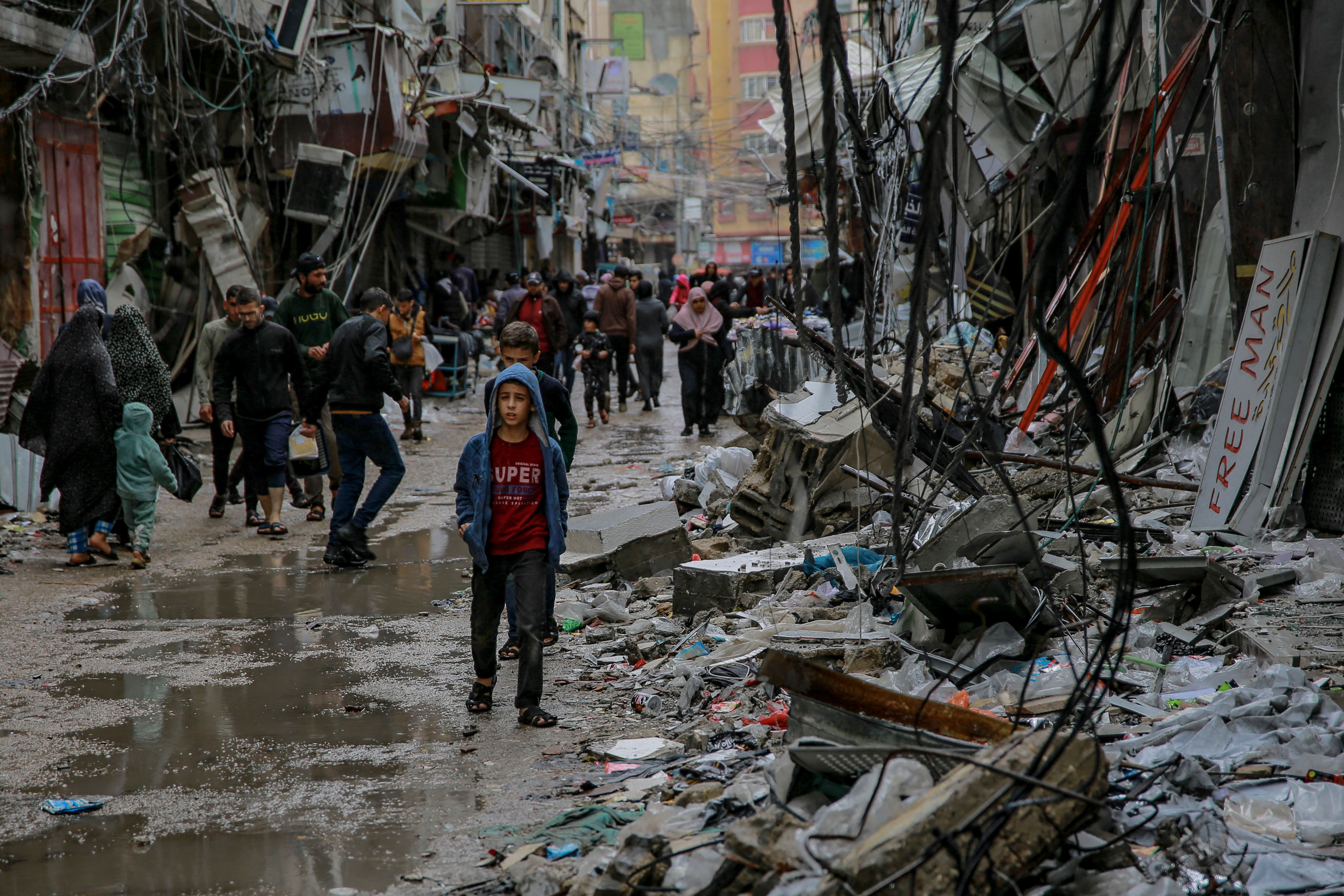 Palestinians walk amid debris of buildings hit in Israeli strikes, near Al-Zawiya market in Gaza City.