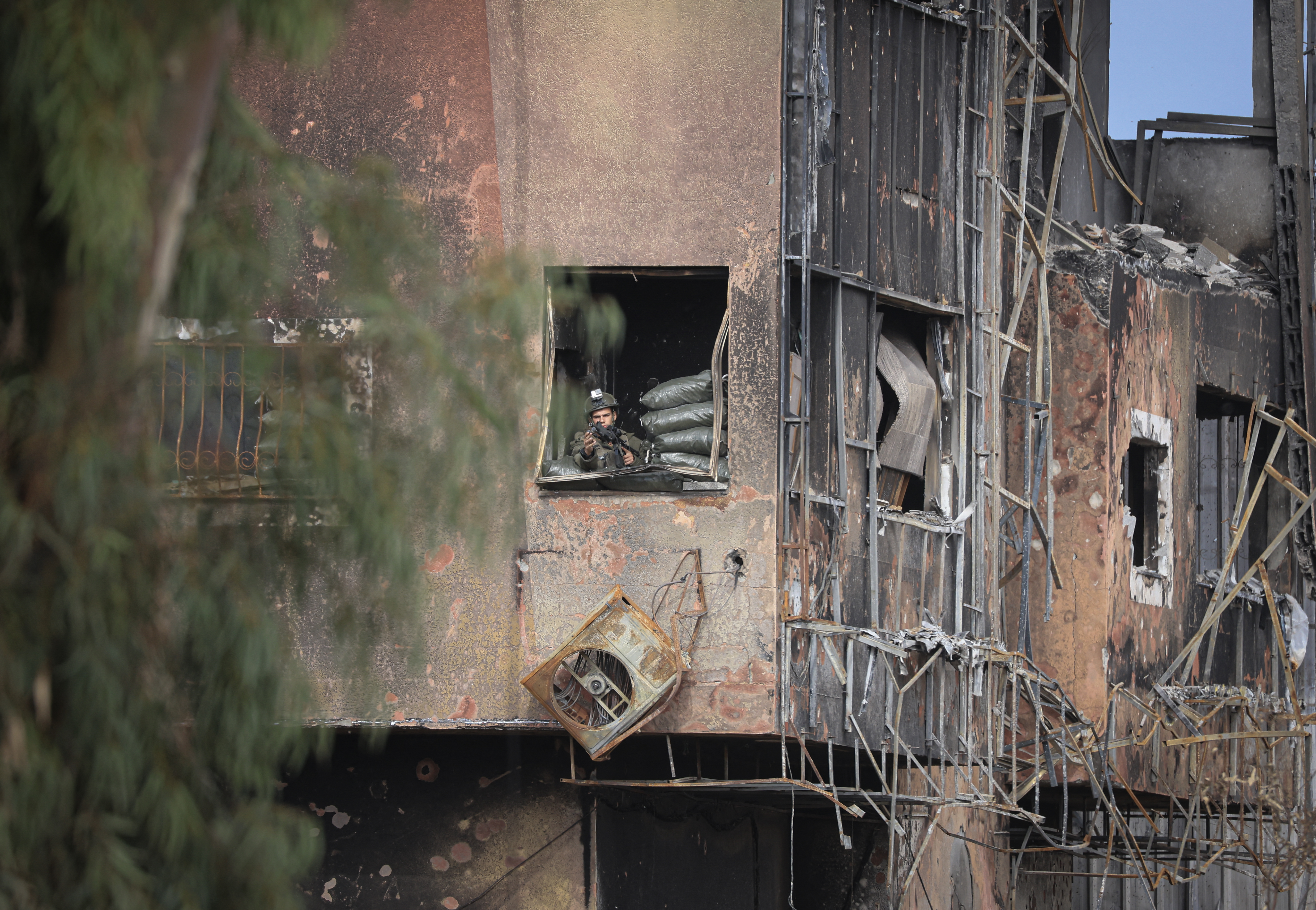 An Israeli soldier takes position within a damaged building to monitor the Salaheddine road in the Zeitoun district on the southern outskirts of Gaza city used by Palestinians leaving the city to the relatively safer south of the Gaza Strip.