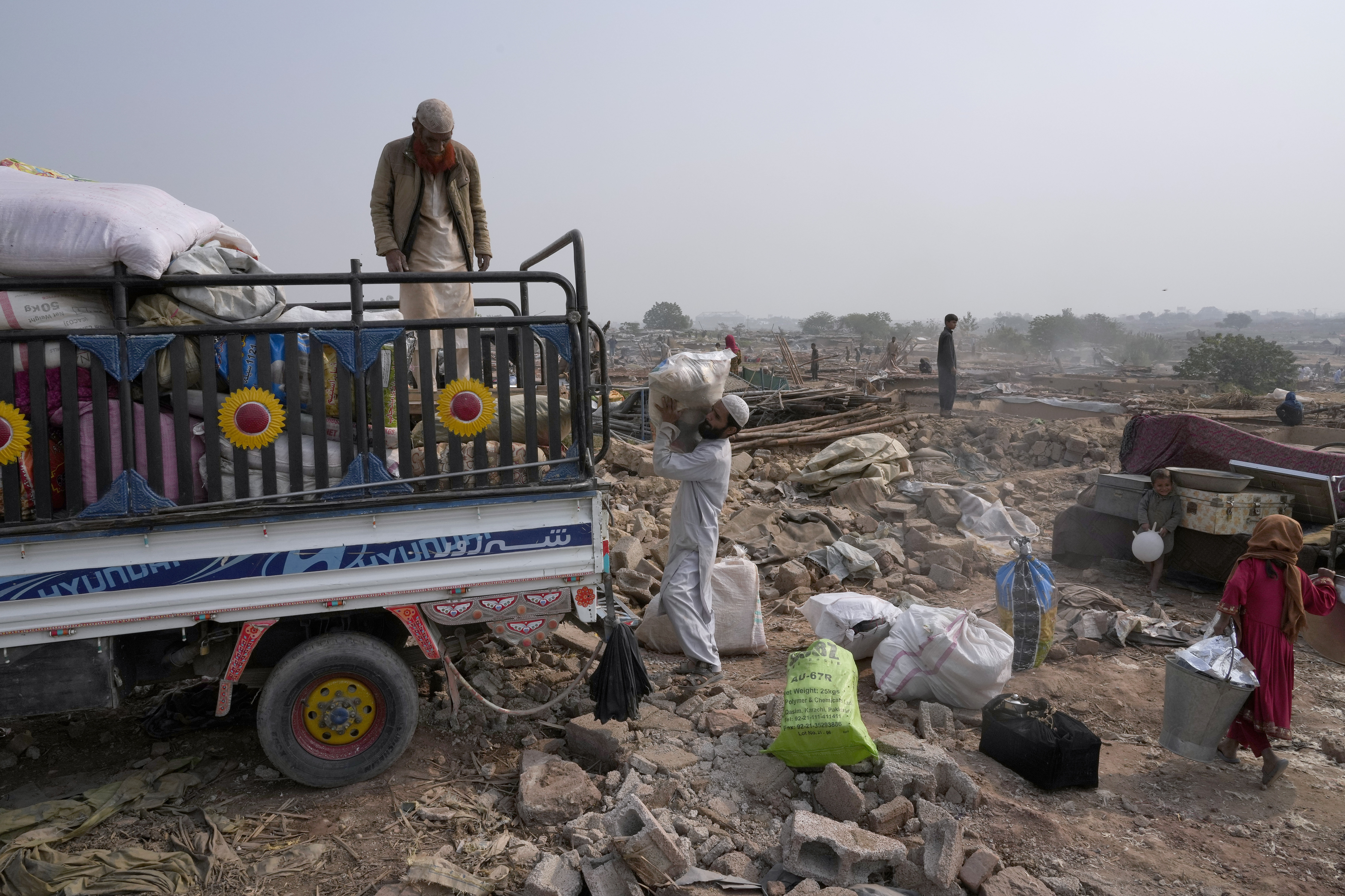 Afghans load their belongings in a vehicle after retrieving them from their damaged mud homes demolished by authorities during a crackdown against an illegal settlement and immigrants, on the outskirts of Islamabad, Pakistan.