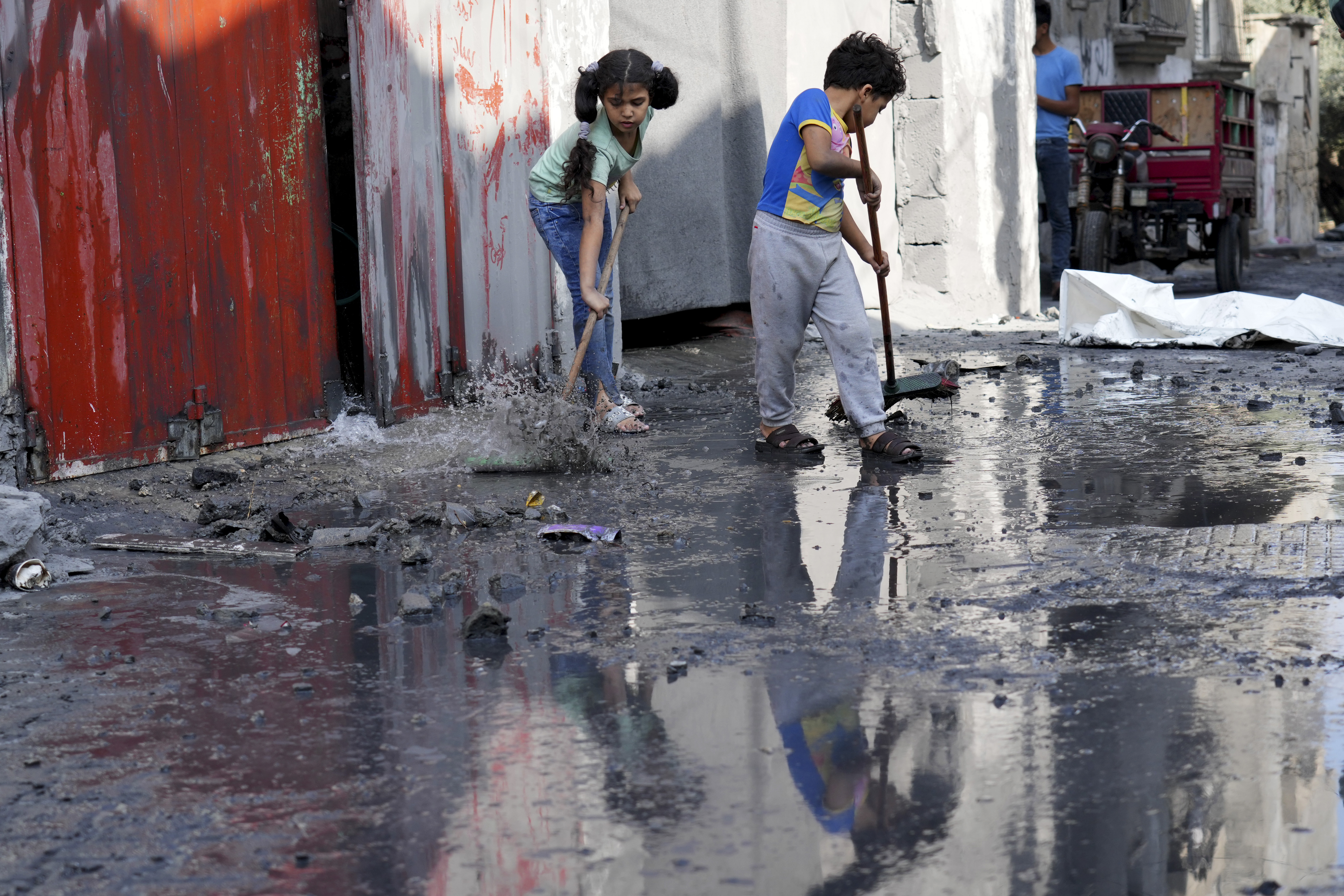 Palestinian kids mop outside their home after the Israeli bombardment in the Maghazi refugee camp