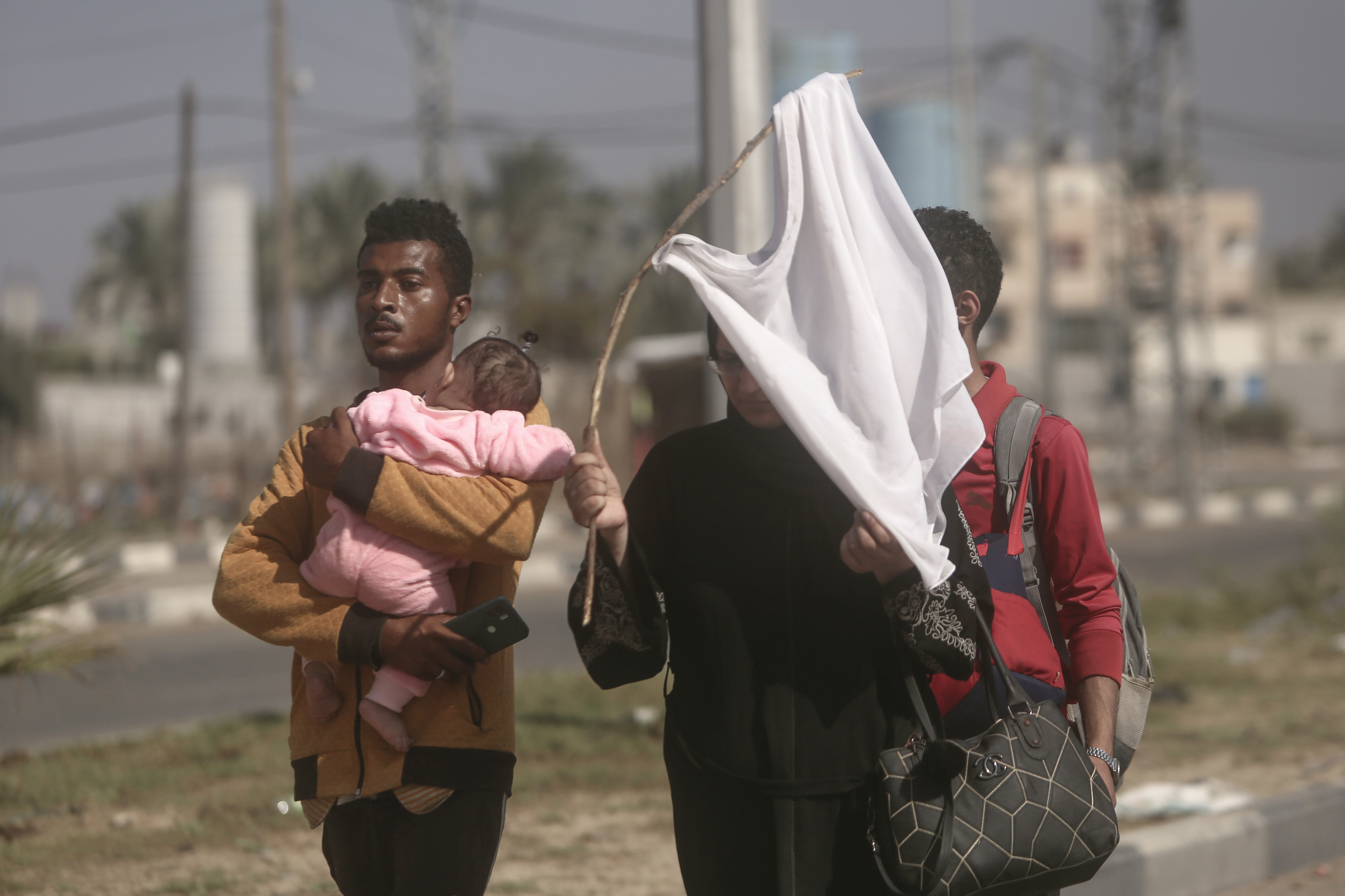 A woman holds-up a white T-shirt trying to prevent being shot, as Palestinians flee Gaza City to the southern Gaza Strip on Salah al-Din street in Bureij, Tuesday.