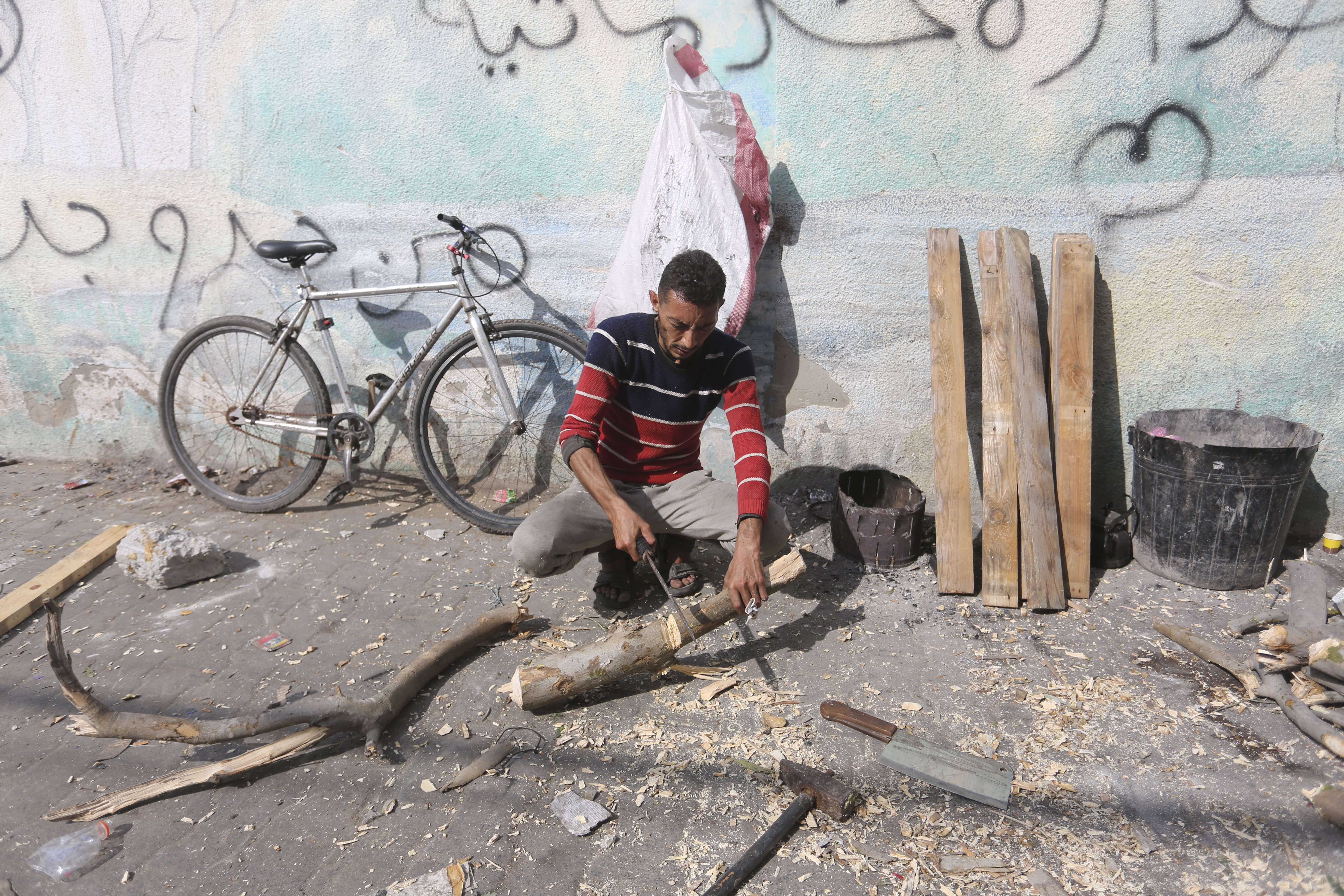 A Palestinian cuts wood during the ongoing Israeli bombardment of the Gaza Strip in Rafah