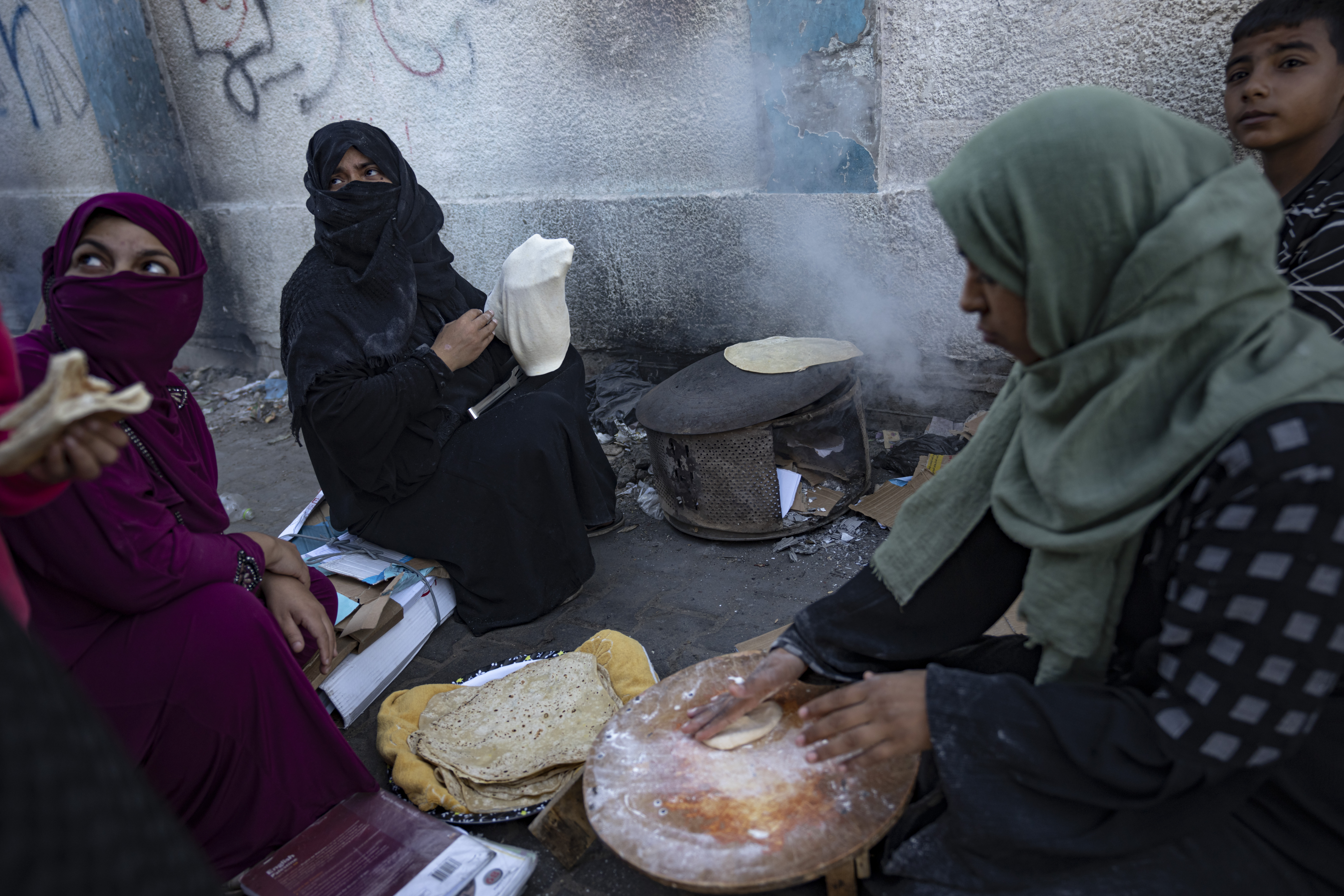 Palestinian women bake bread during the ongoing Israeli bombardment of the Gaza Strip in Khan Younis