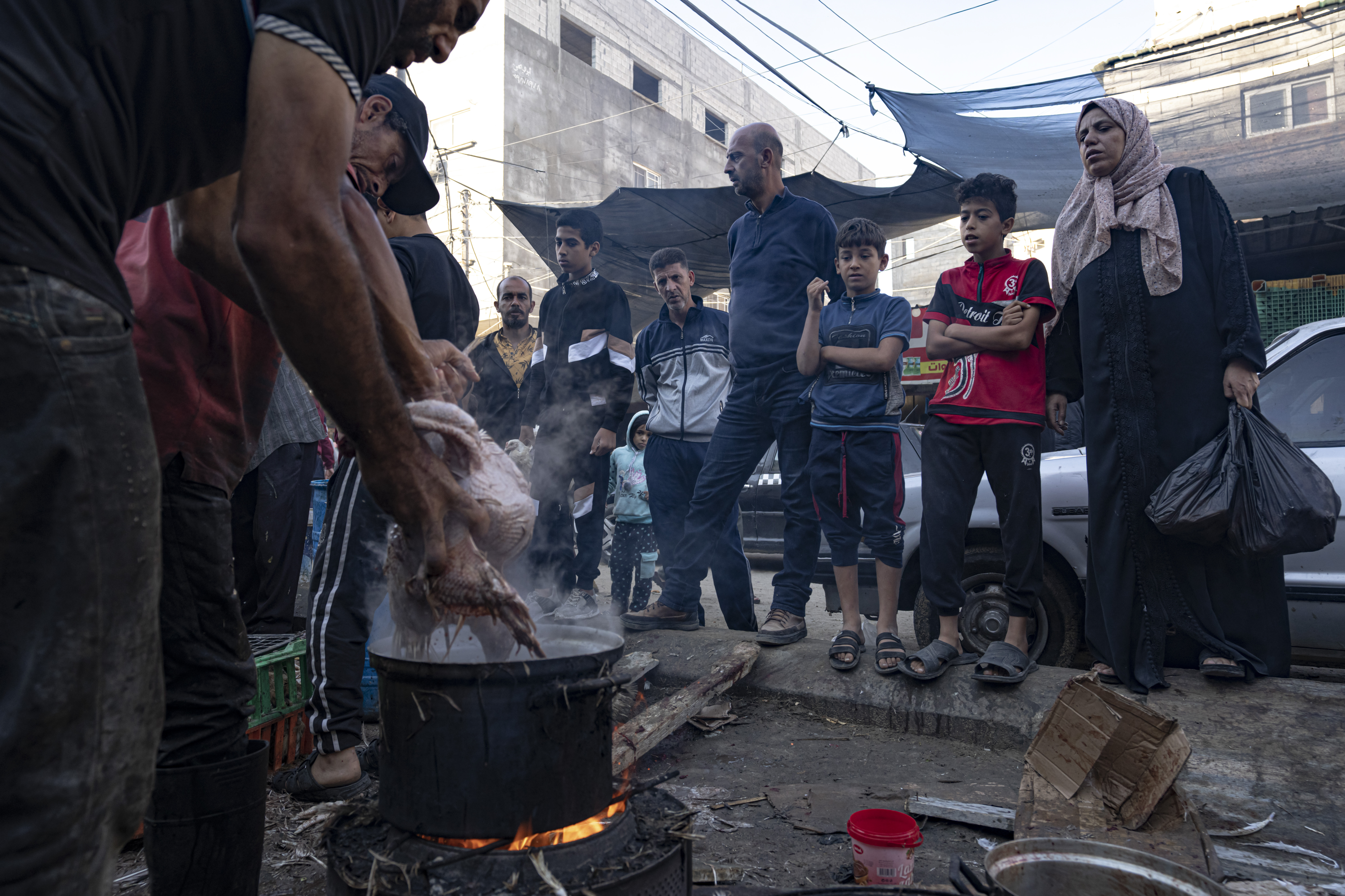 Palestinians wait to cook chickens during the ongoing Israeli bombardment of the Gaza Strip in Khan Younis