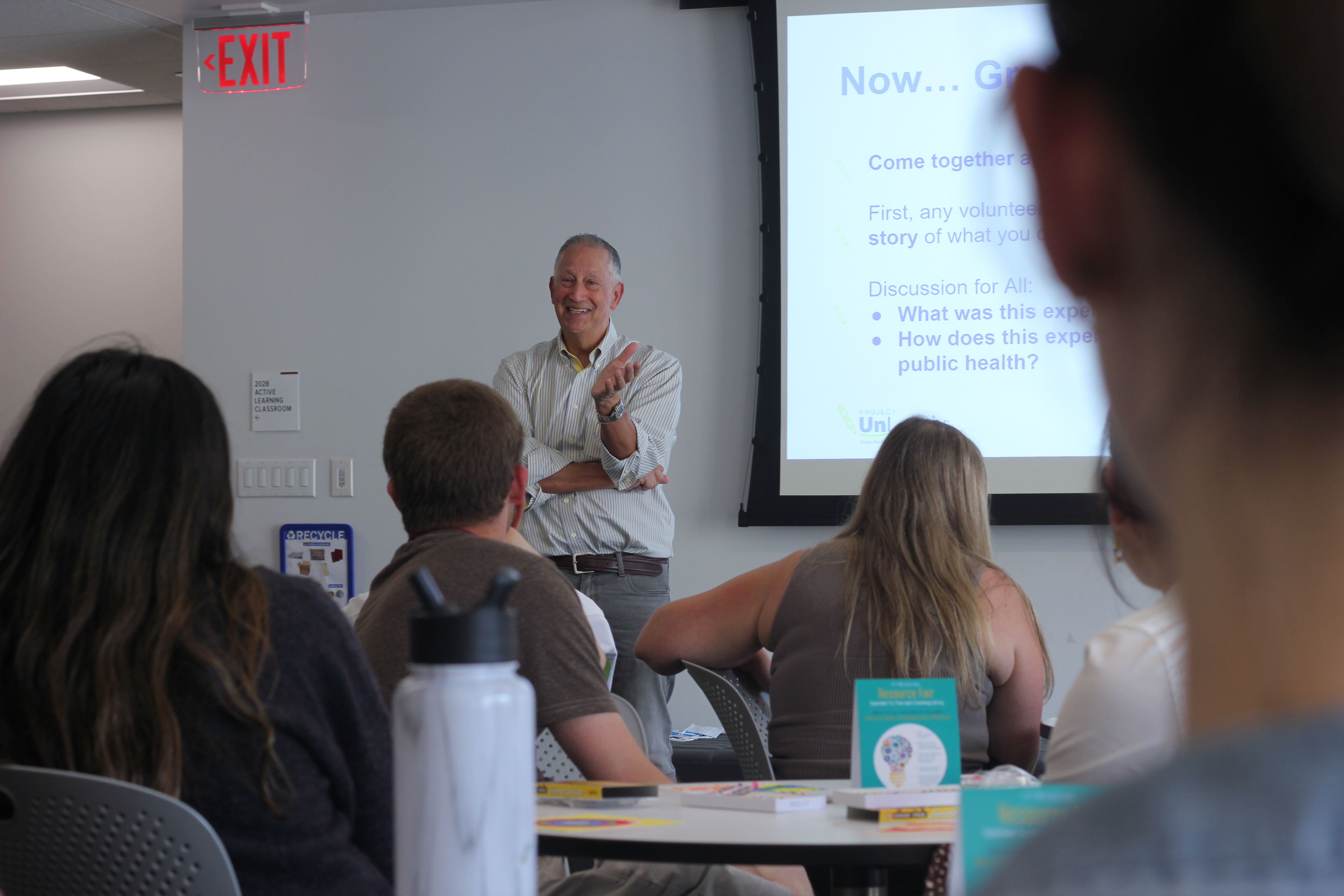 Jeremy Nobel stands in front of a classroom, next to a screen projecting course material.