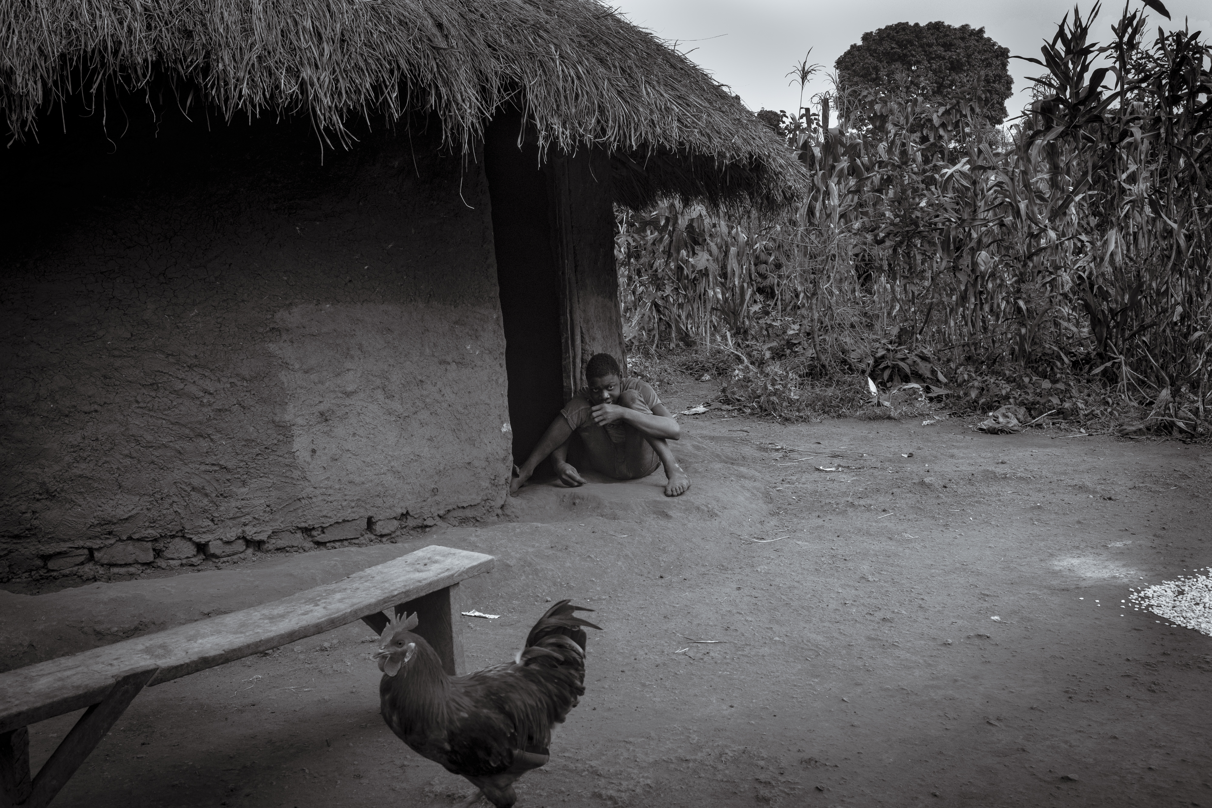 Perez Mwase sits at the doorway of his home