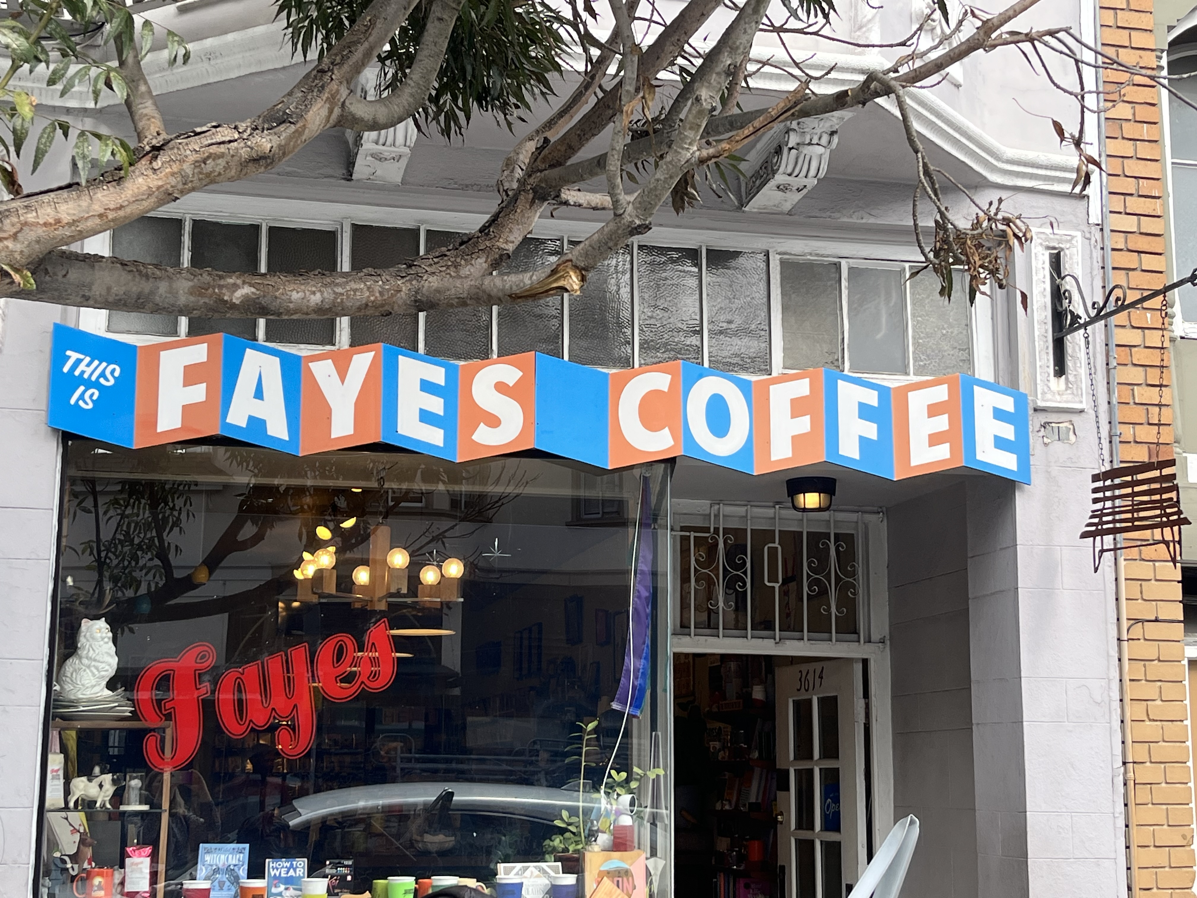 An exterior view of the San Francisco coffee shop Fayes, showing a red-and-blue sign with the café's name written in blocks.
