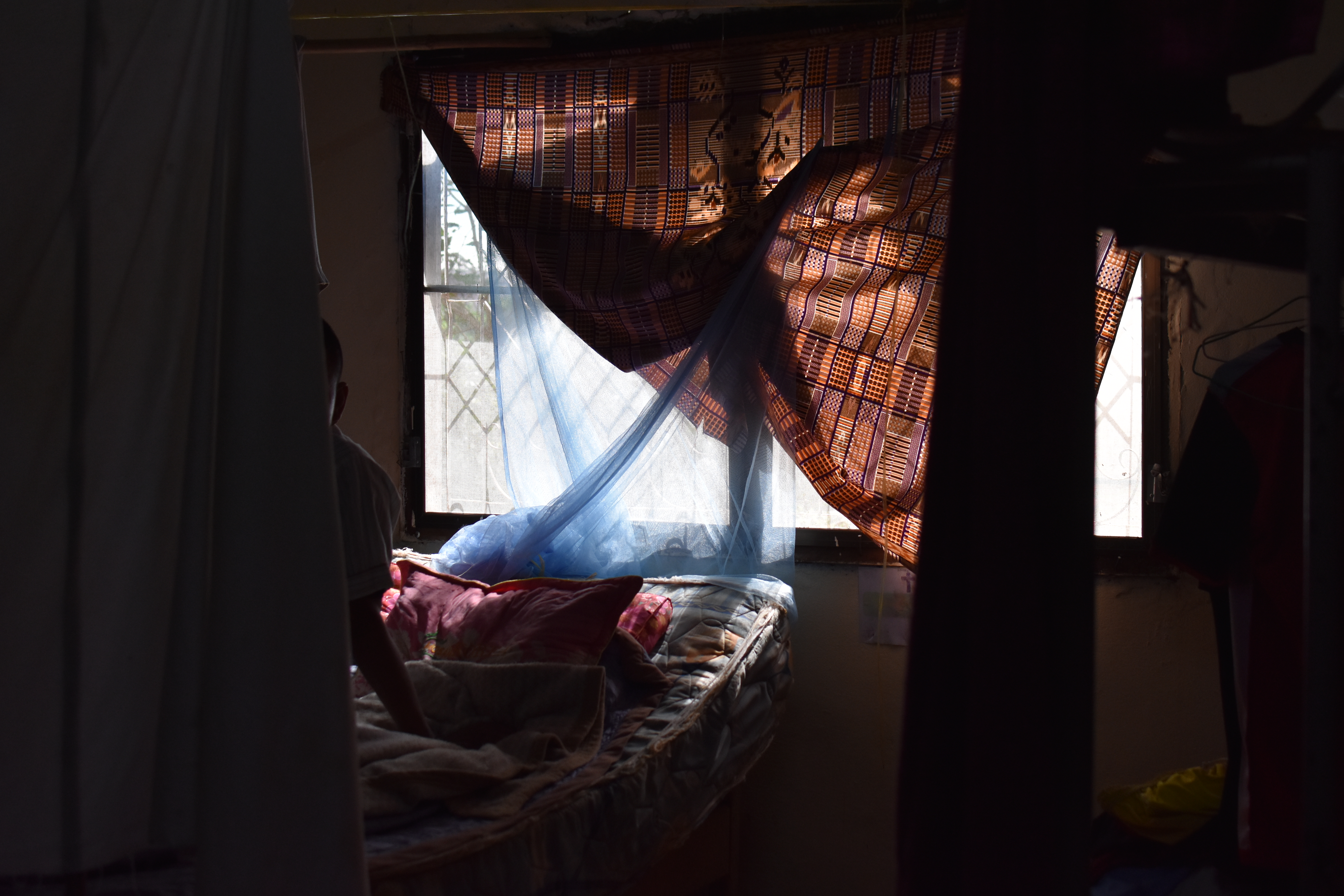 A dorm room for the users at the Transformation Centre A curtain is across the window leaving the room in shadows