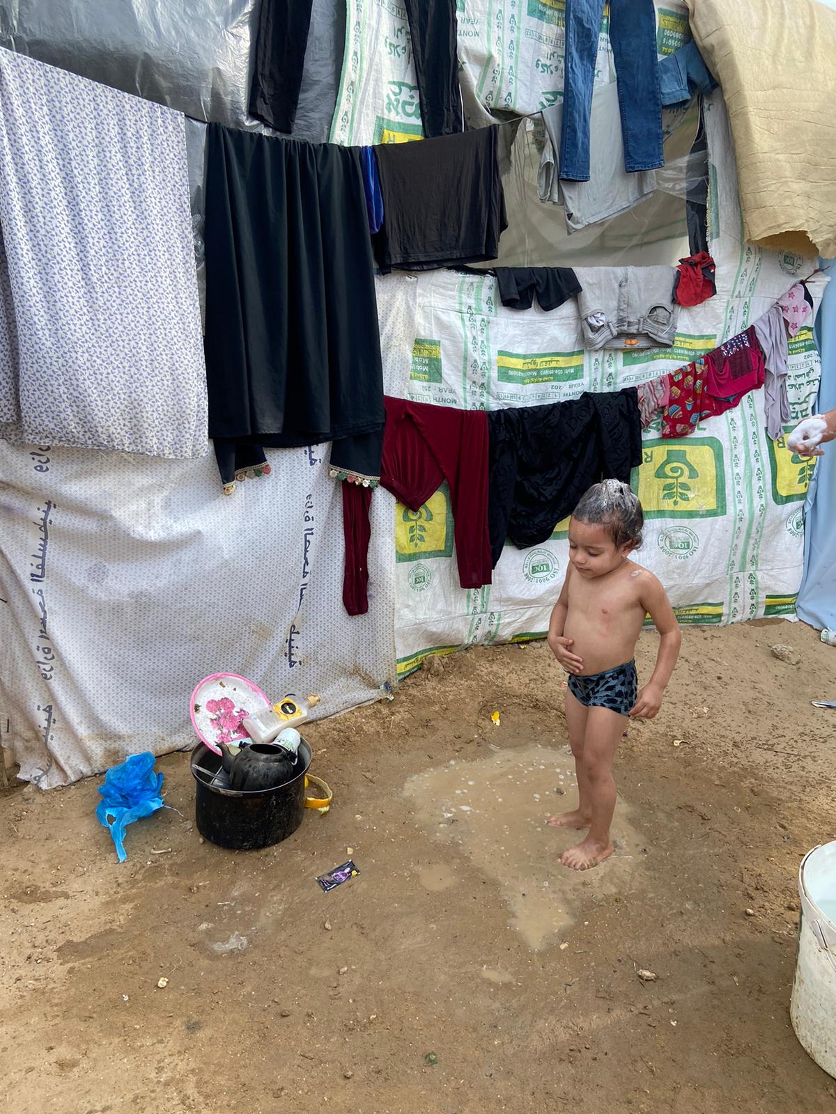 A child bathing outside a tent. More than half of Gaza's population has been displaced by Israel's war on the narrow strip [Maram Humaid/Al Jazeera]