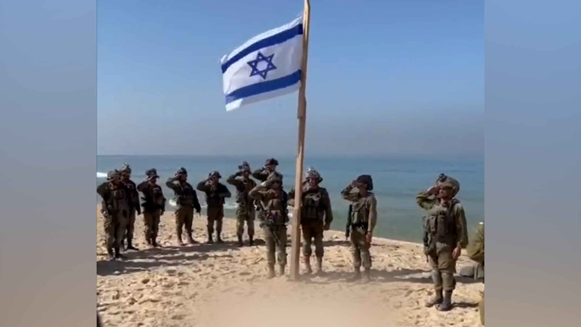 A screenshot of a video showing Israeli soldiers raising the Israeli flag on a beach in Gaza in November 2023 [Al Jazeera/Screenshot]