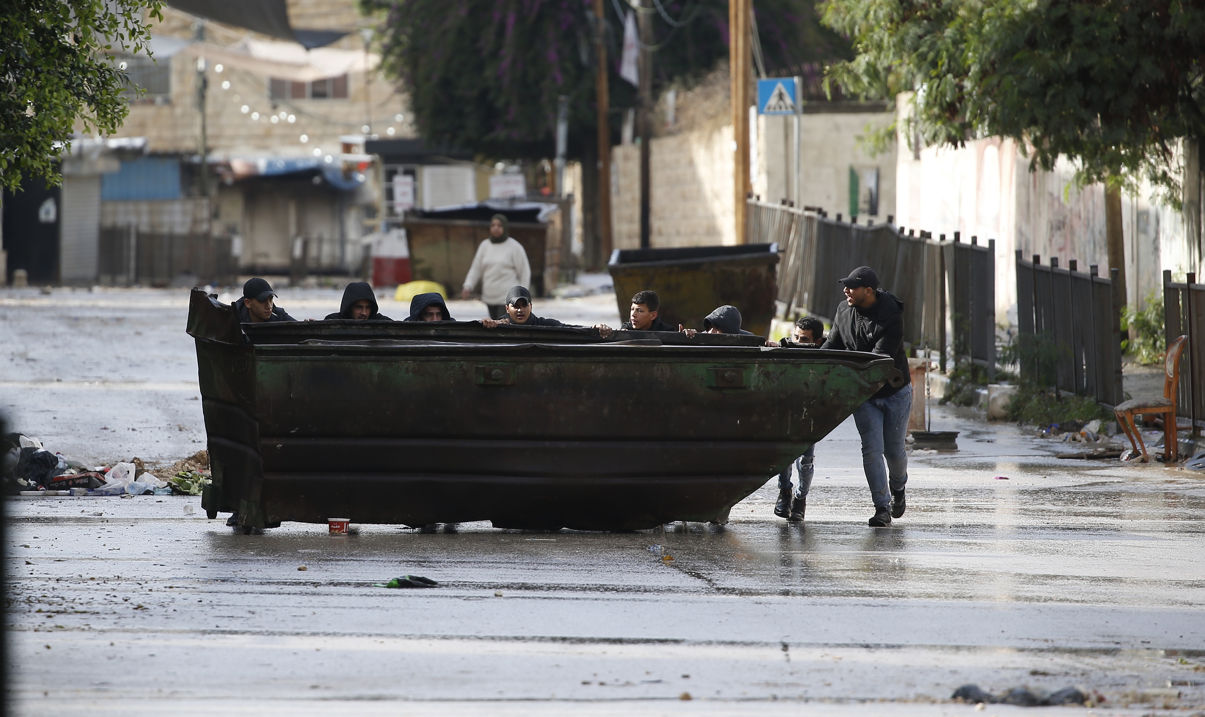 Men attempt to block a road as the Israel Defence Force conduct a raid for the second day at a refugee camp near the West Bank city of Jenin, 13 December 2023.