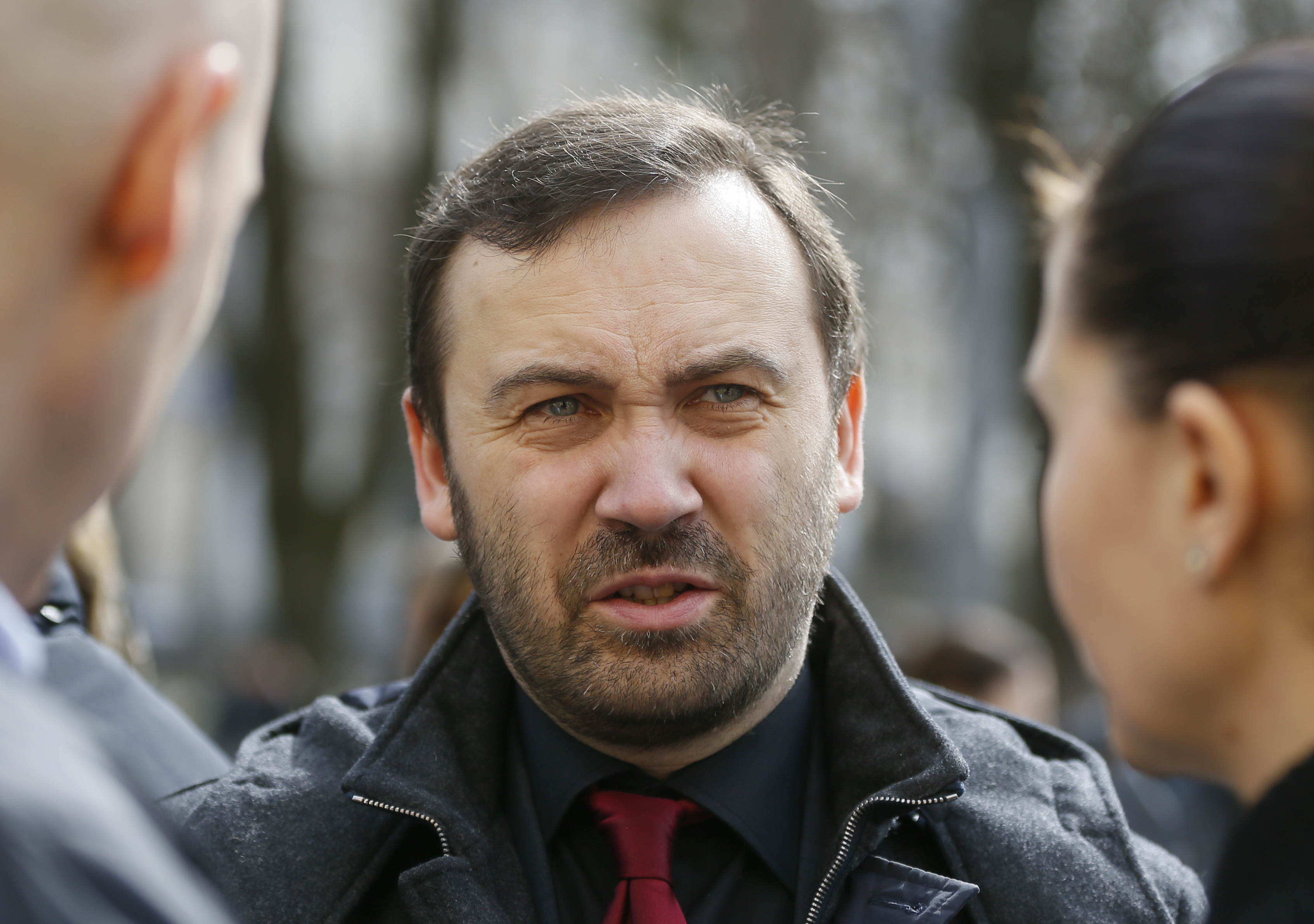 Russian former parliamentarian Ilya Ponomarev speaks with acquaintances after a burial service