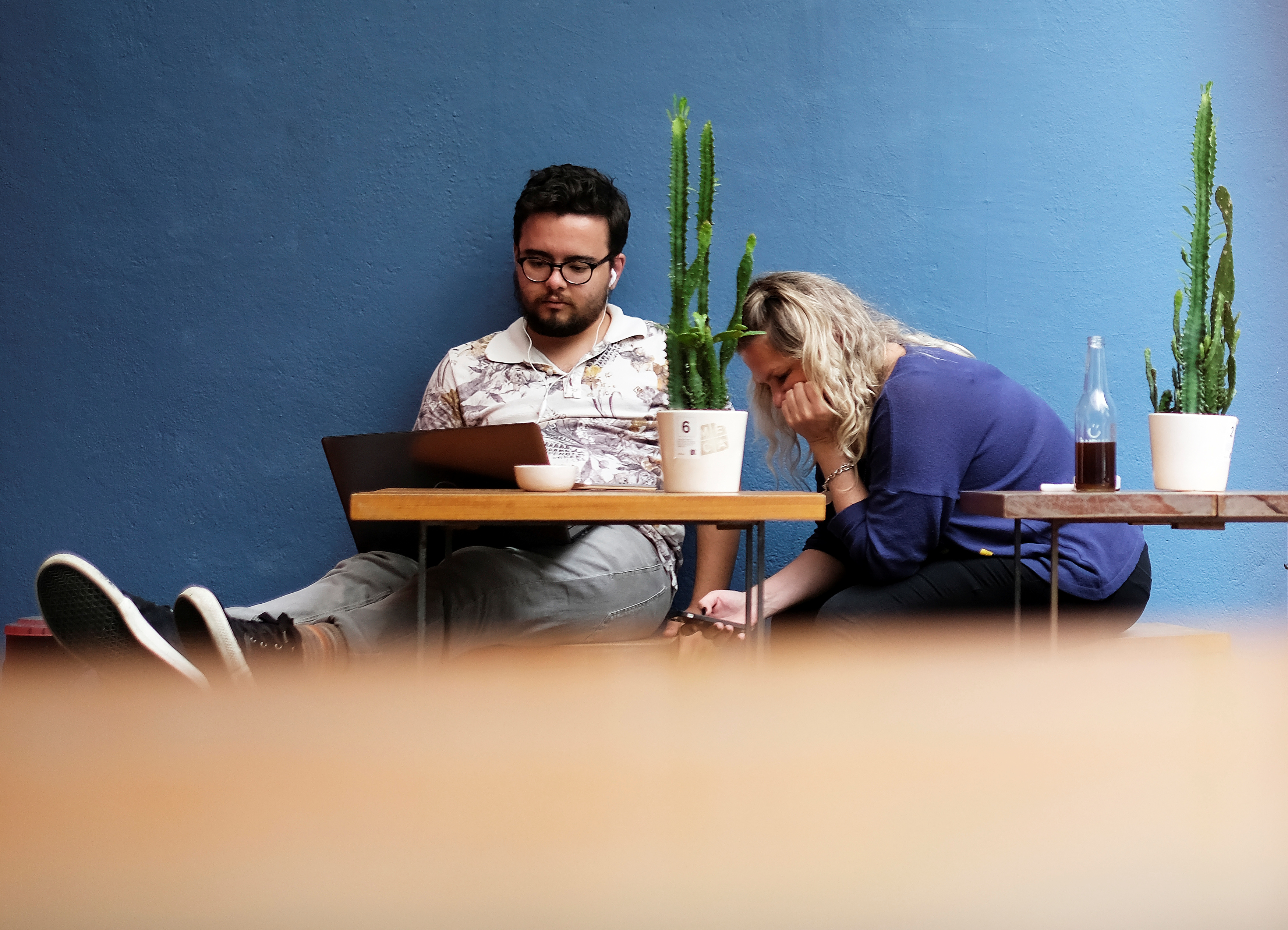 A man uses his computer next to a woman writing a message on her mobile phone at a cafe in Sao Paulo, Brazil October 17, 2017