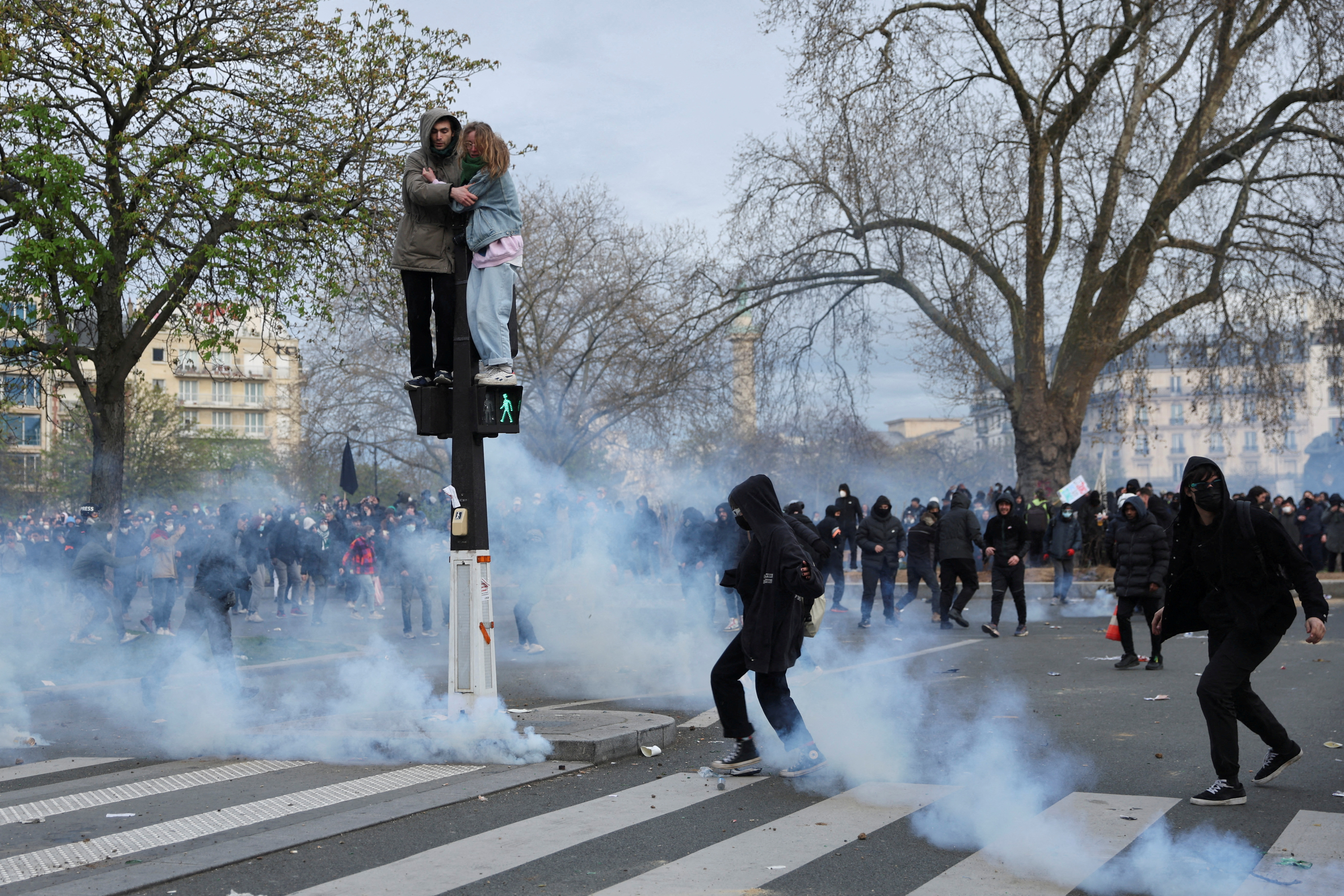 People stand on a pedestrian traffic light during clashes at a demonstration as part of the tenth day of nationwide strikes and protests against French government's pension reform in Paris, France, March 28