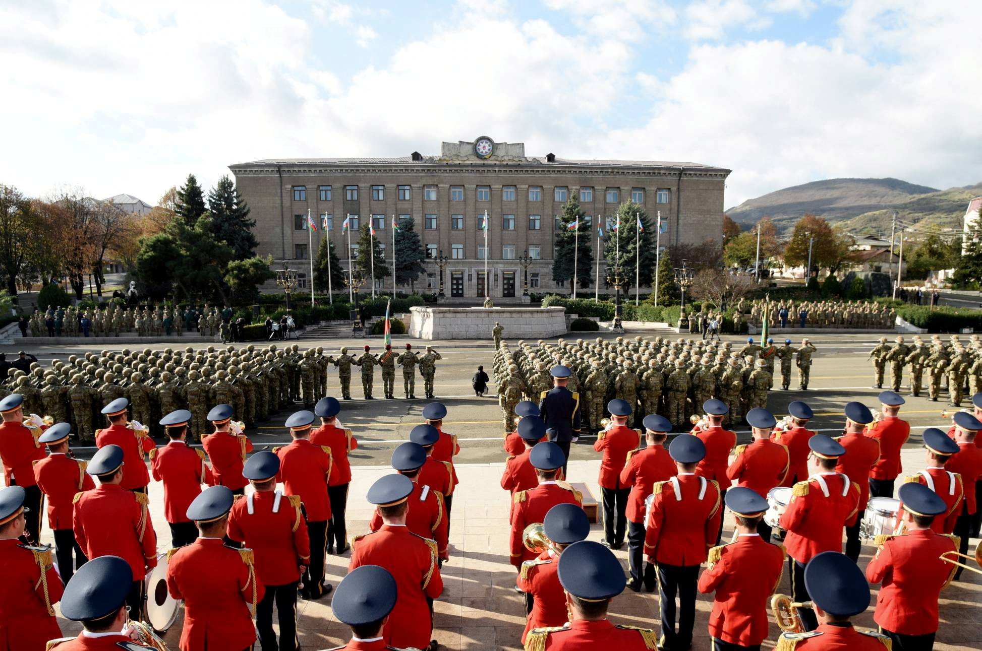 Soldiers from Azerbaijan on parade in Nagorno-Karabakh region's capital city. There is a miitary band in red ceremonial uniforms.
