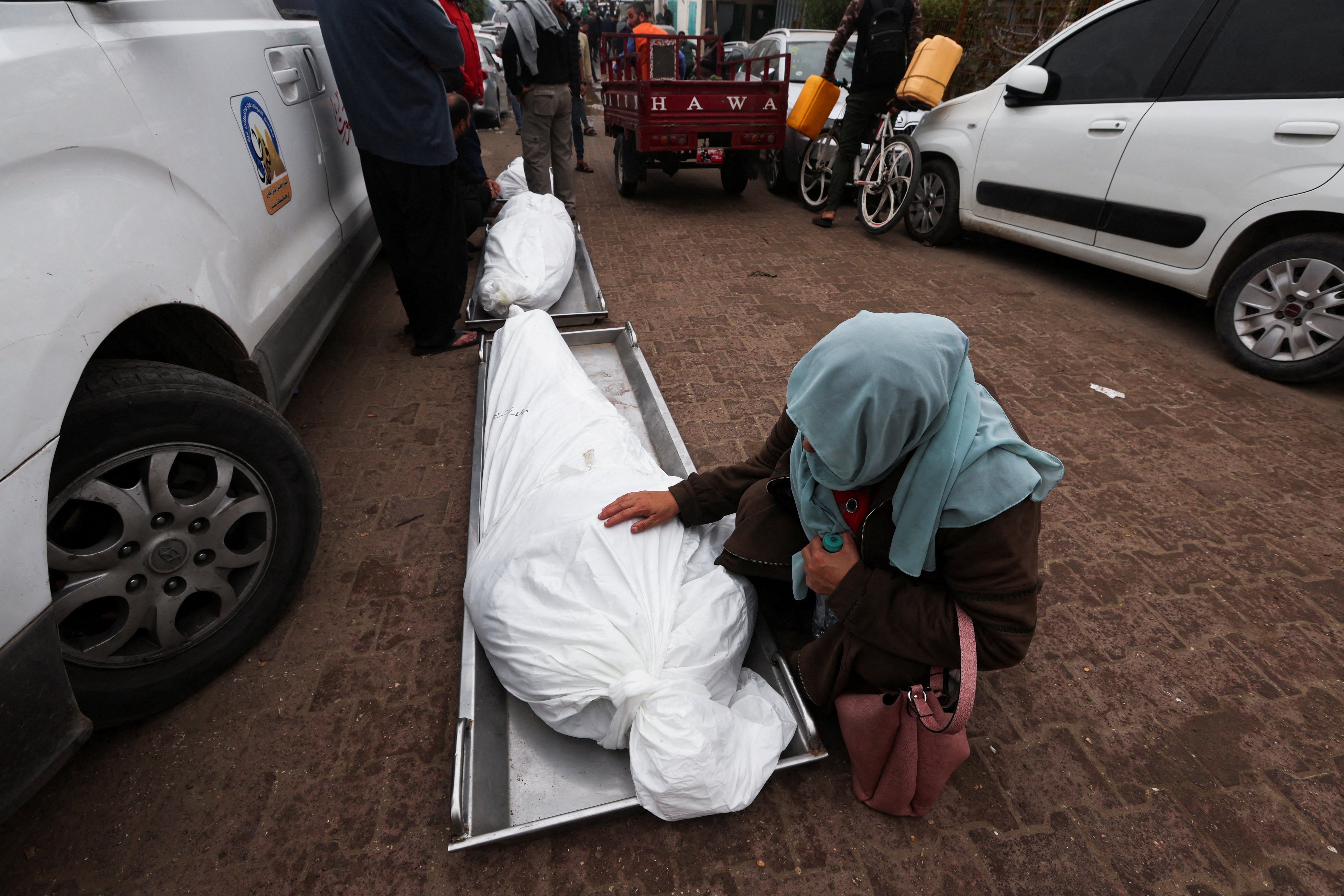A Palestinian woman kneels near the body of a Palestinian person who was killed during Israeli strikes on Ma'an school east of Khan Younis