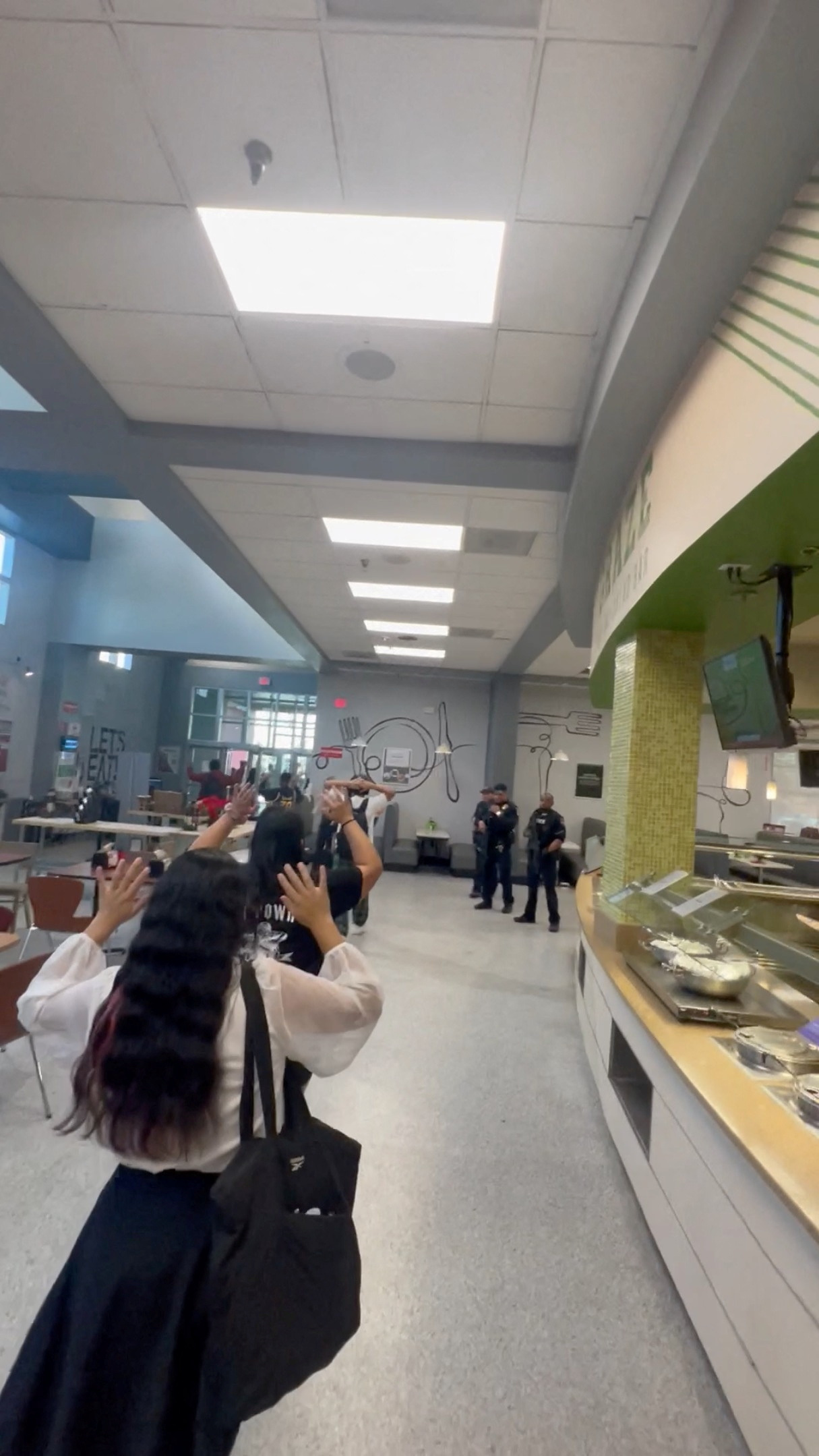 Students evacuate the campus with their hands held up, following a shooting