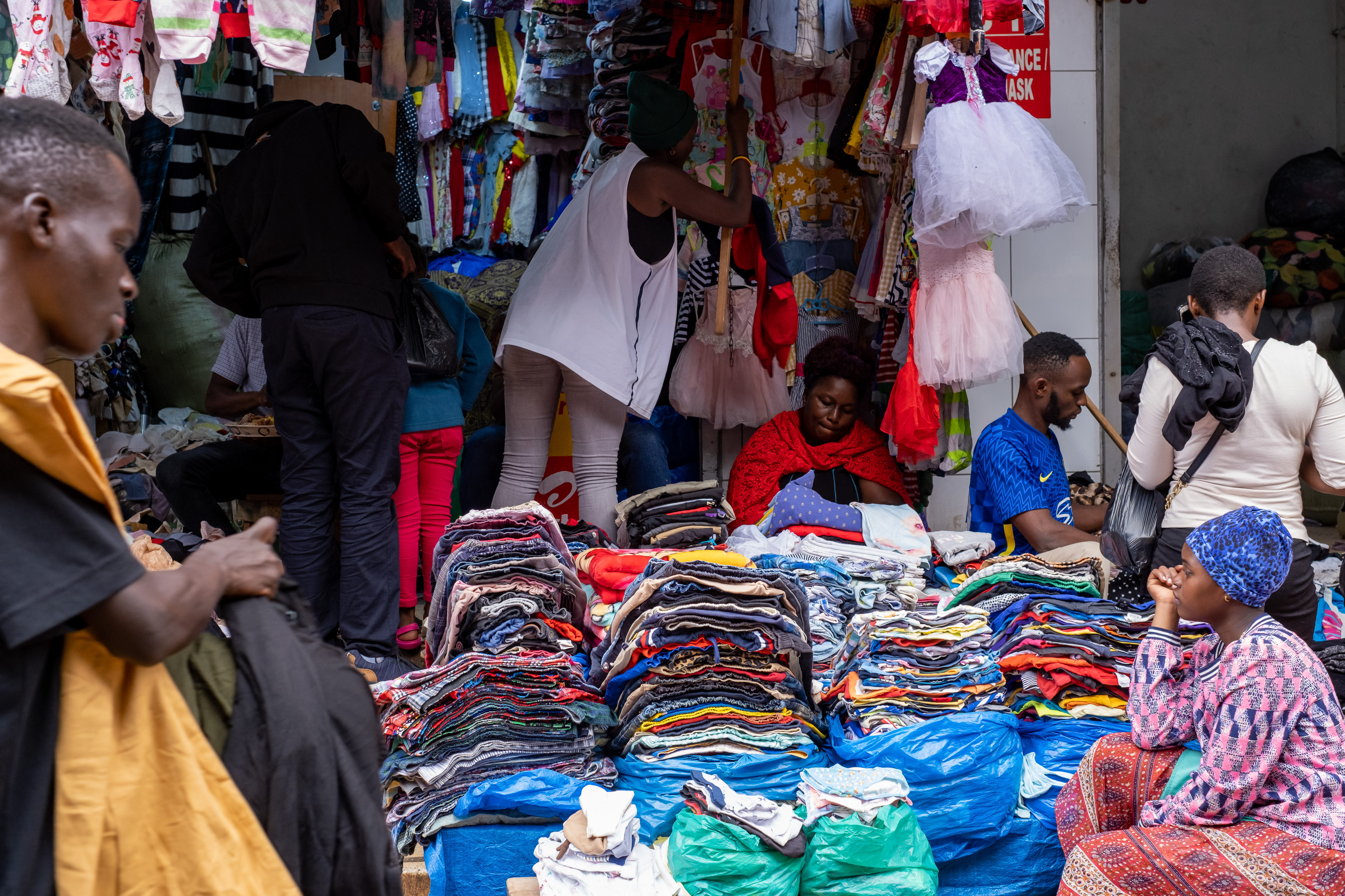 Sellers offering second-hand clothes wait for costumers at a market in Kampala.