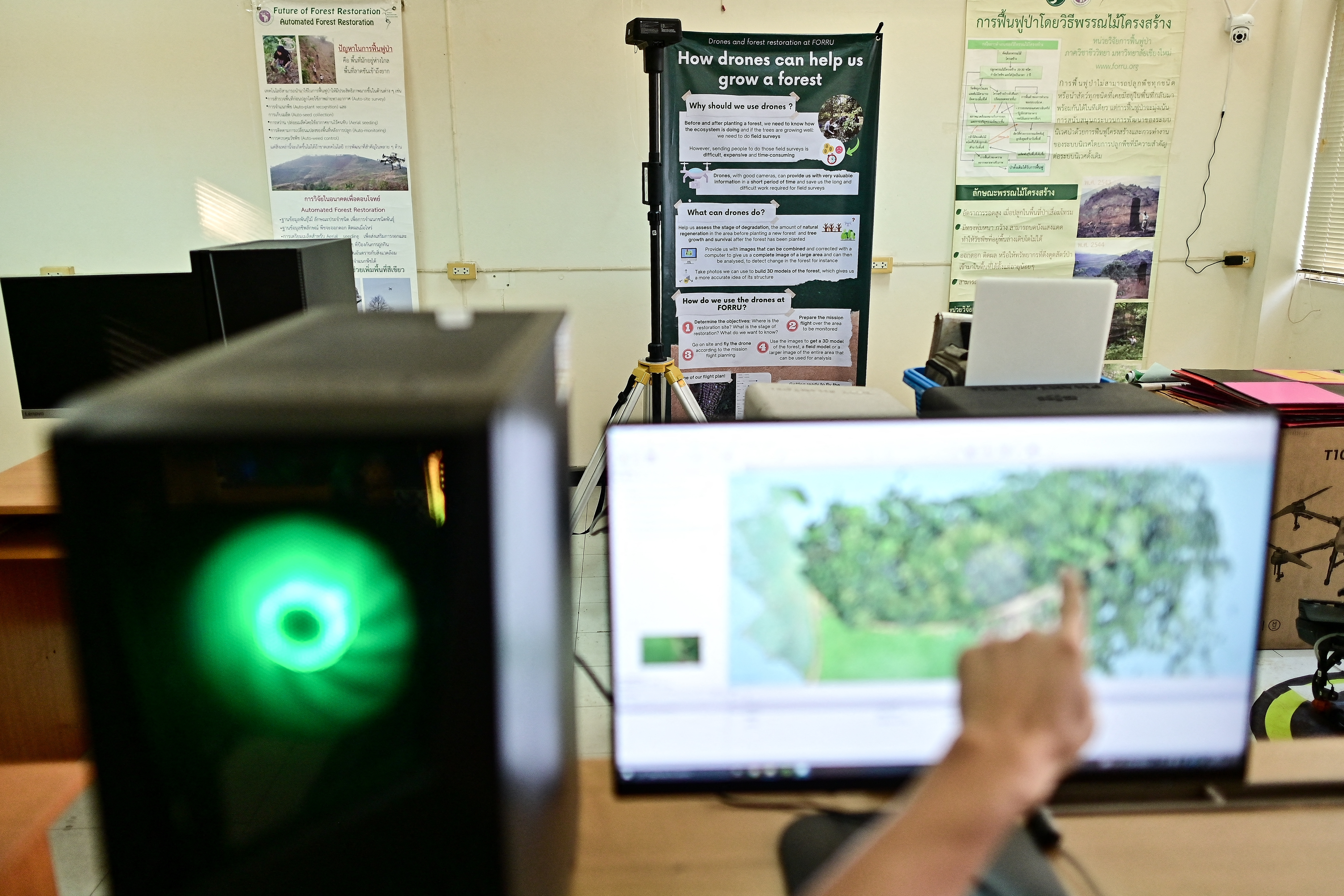 This picture taken on November 22, 2023 shows Chiang Mai University's Forest Restoration Research Unit (FORRU) field research officer Worayut Takaew pointing to a computer screen while creating a 3D model of overlapping images taken from his drone at his lab in Chiang Mai.