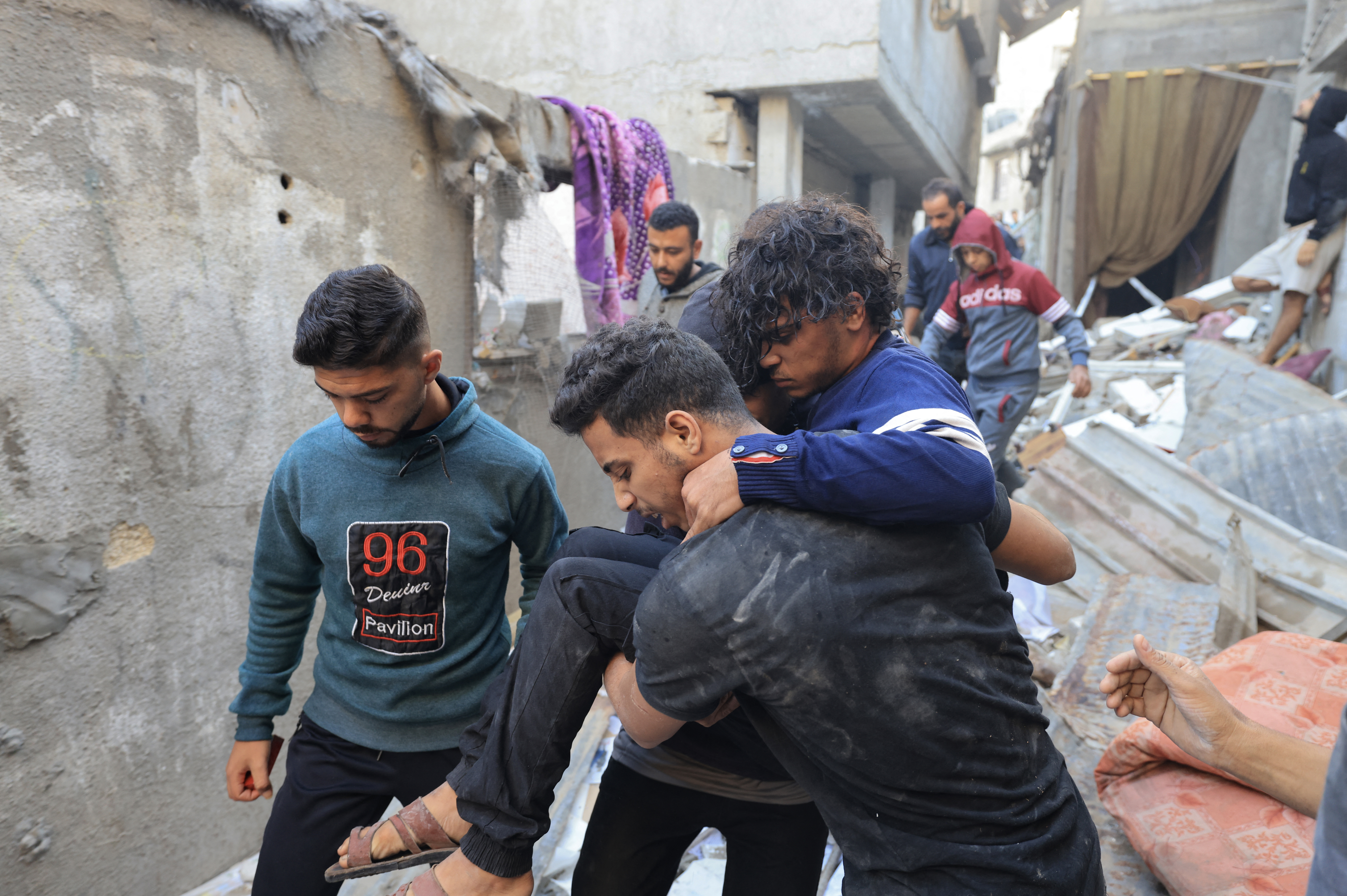 An injured man is carried away after a house was hit by Israeli bombing in Khan Yunis in the southern Gaza Strip on December 3