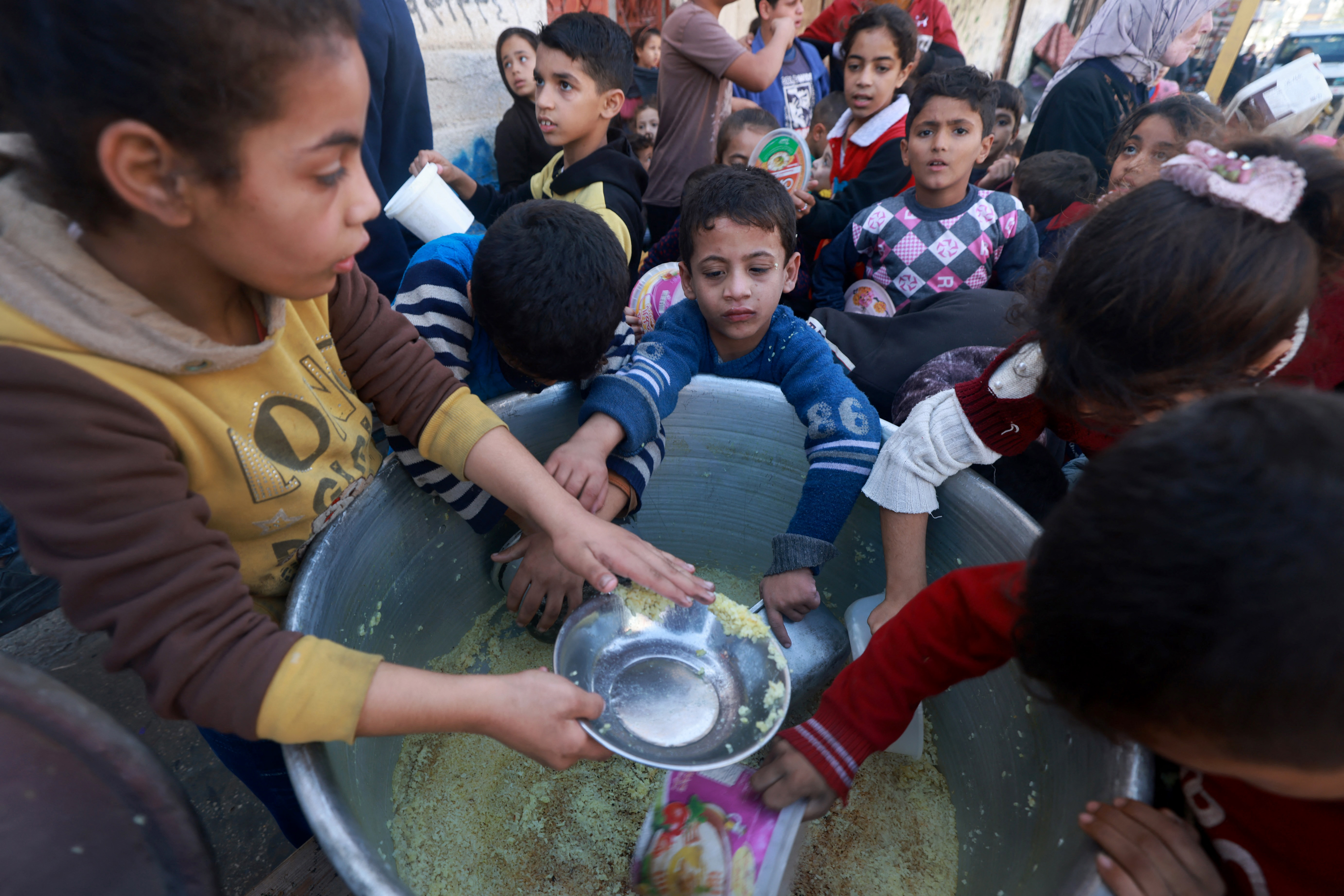 Palestinian children collect food at a donation point provided by a charity group in the southern Gaza Strip city of Rafah.