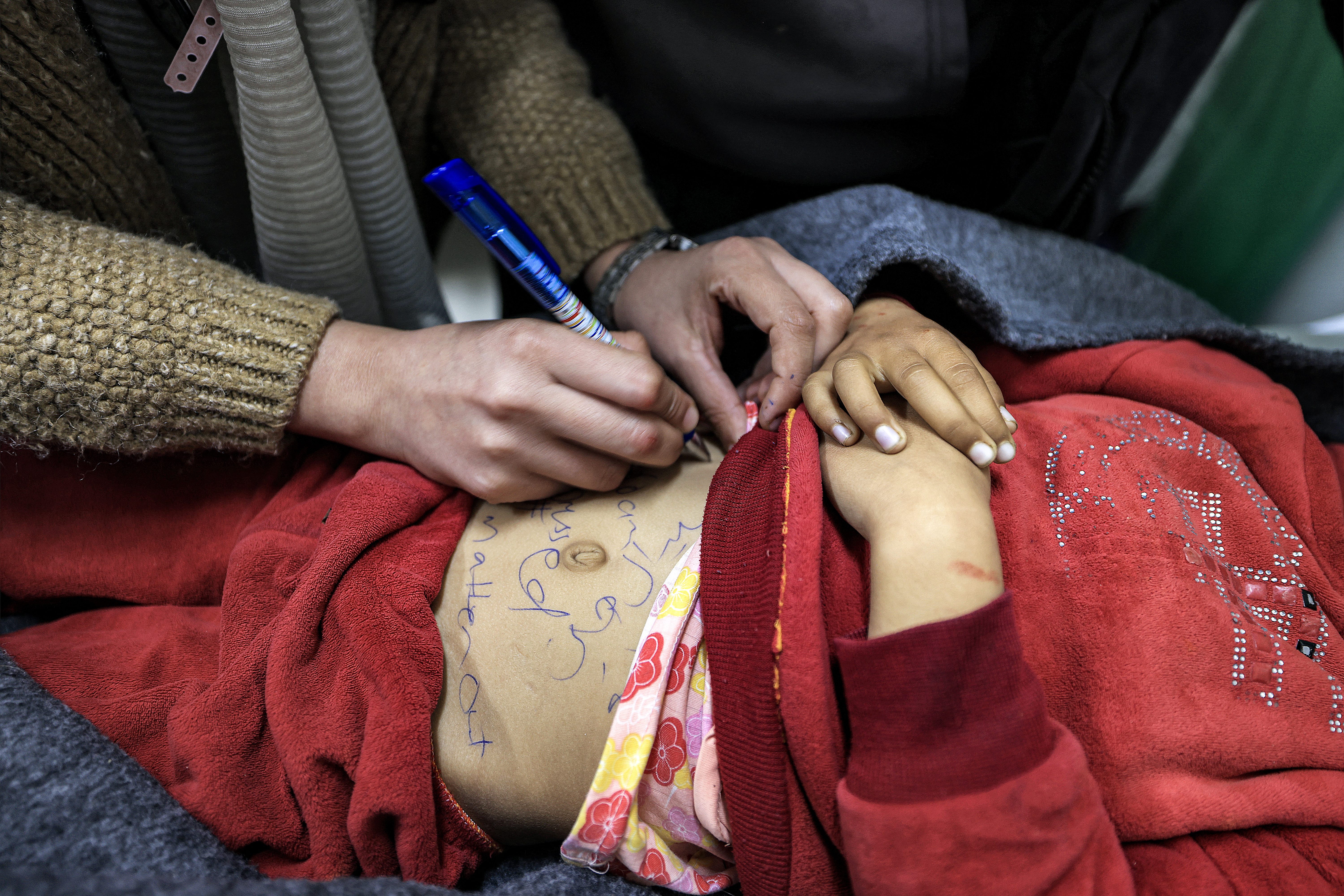 A nurse writes the identification information on the body of Sidal Abu Jamea, a Palestinian girl from Khan Yunis who died overnight while sleeping in a tent from a shrapnel fragment that hit her in the head following Israeli bombardment on a nearby position, at the Kuwaiti Hospital in Rafah in the southern Gaza Strip.