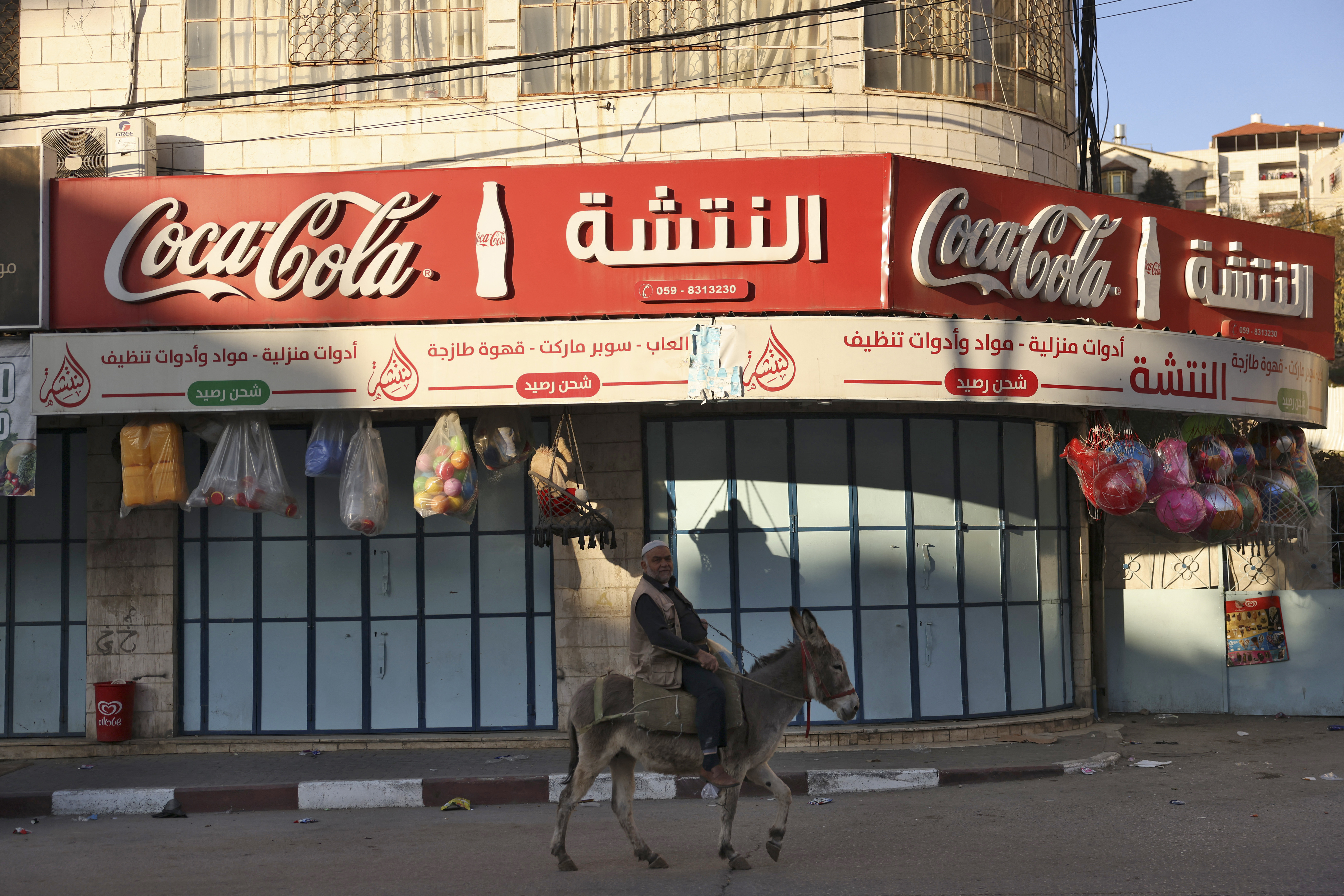 A man rides his donkey past a shuttered shop during a general strike in solidarity with Gaza, in the occupied West Bank city of Hebron, on December 11