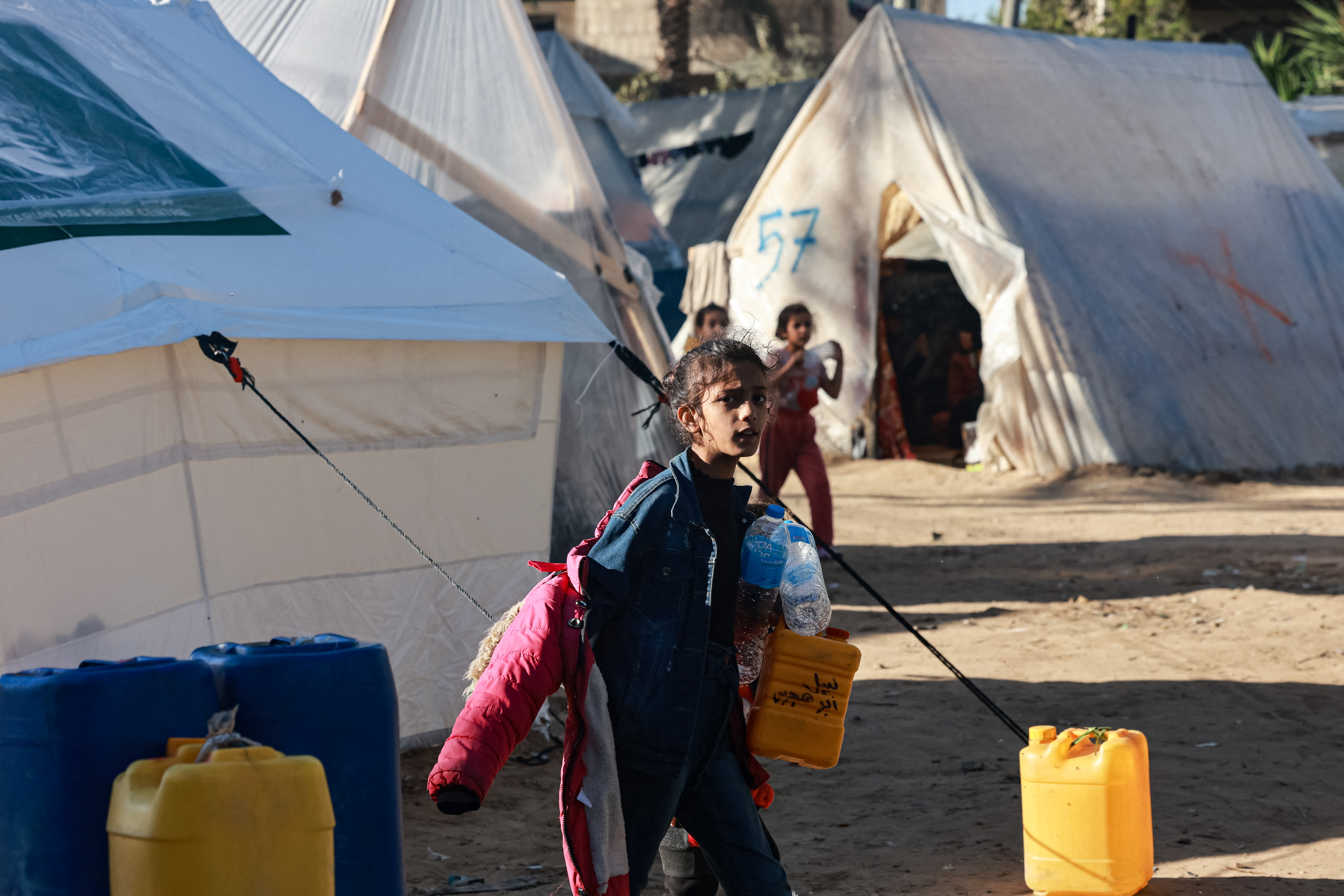 A girl carries containers to fill with water at a camp for displaced Palestinians in Rafah in the southern Gaza Strip.